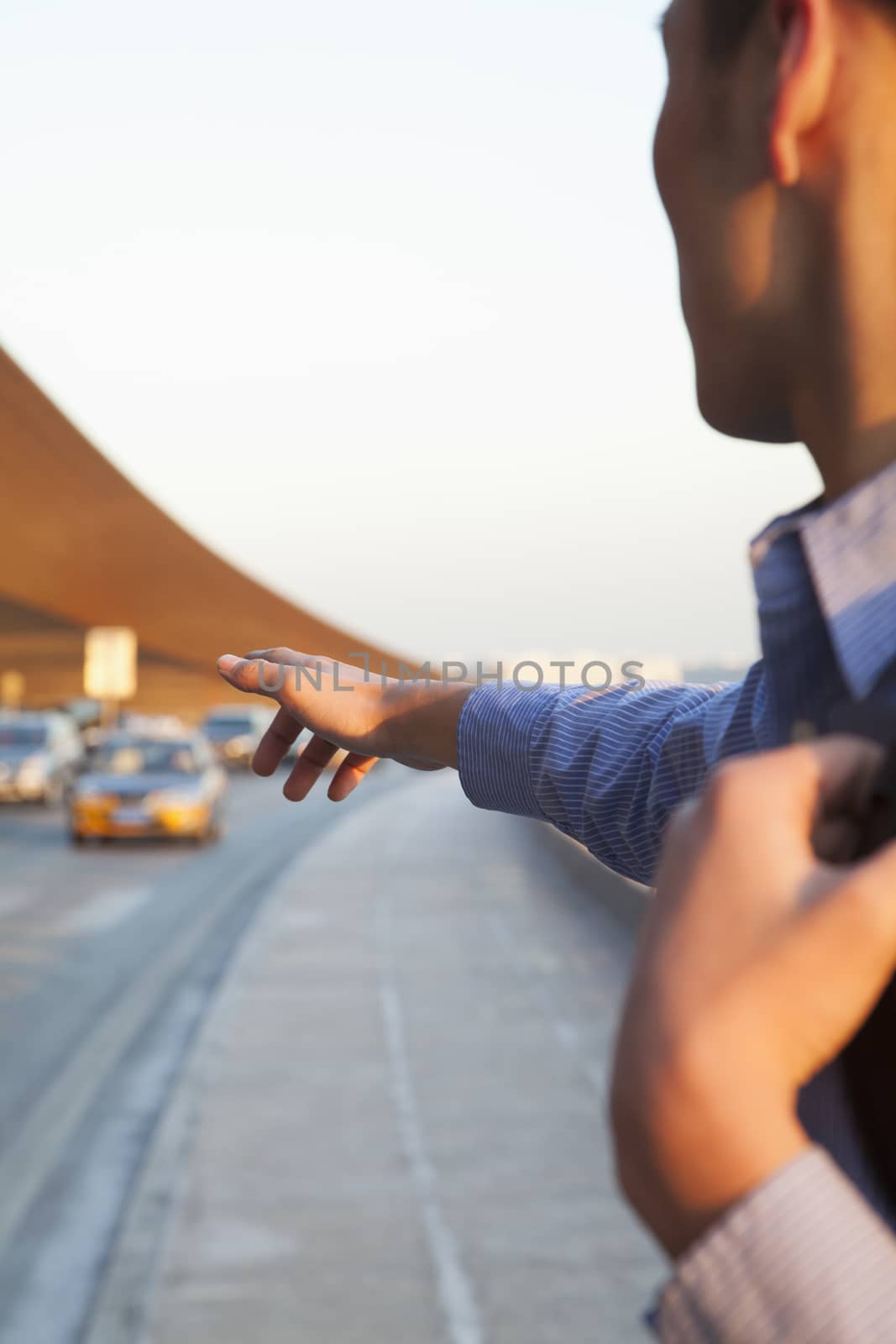 Young traveler hailing a taxi outside of the airport