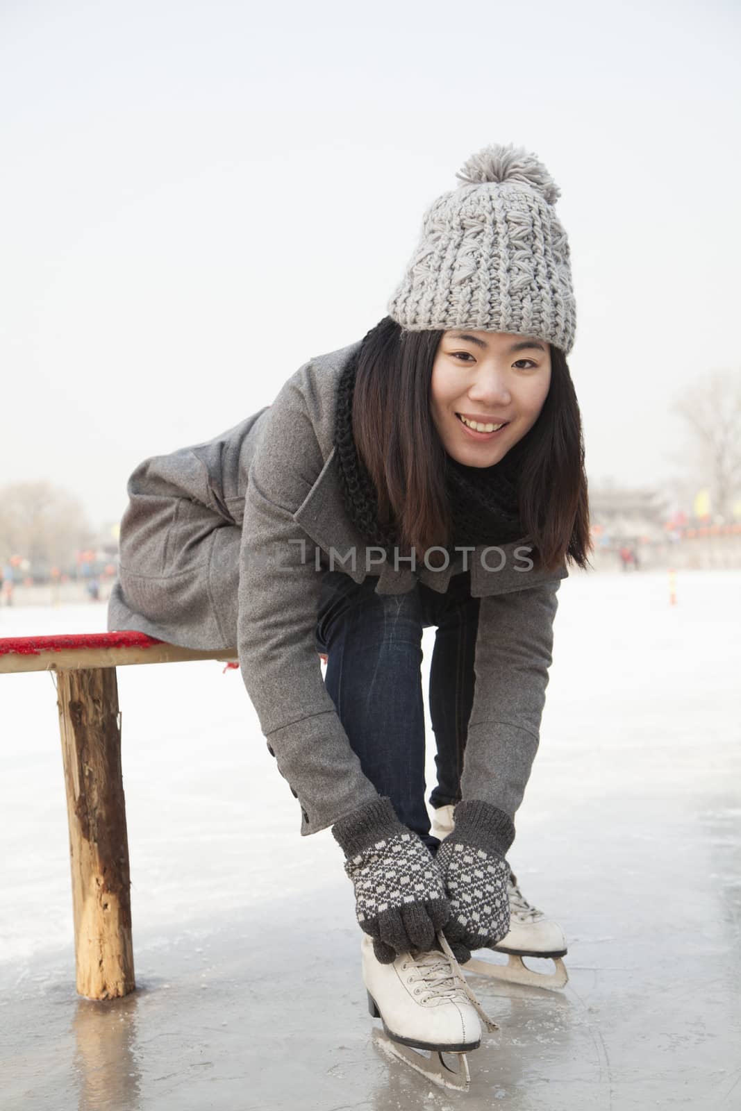 Young woman putting on ice skate, Beijing