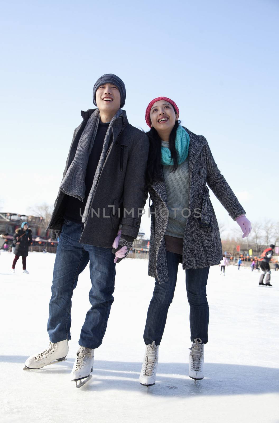 Young couple skating at ice rink by XiXinXing