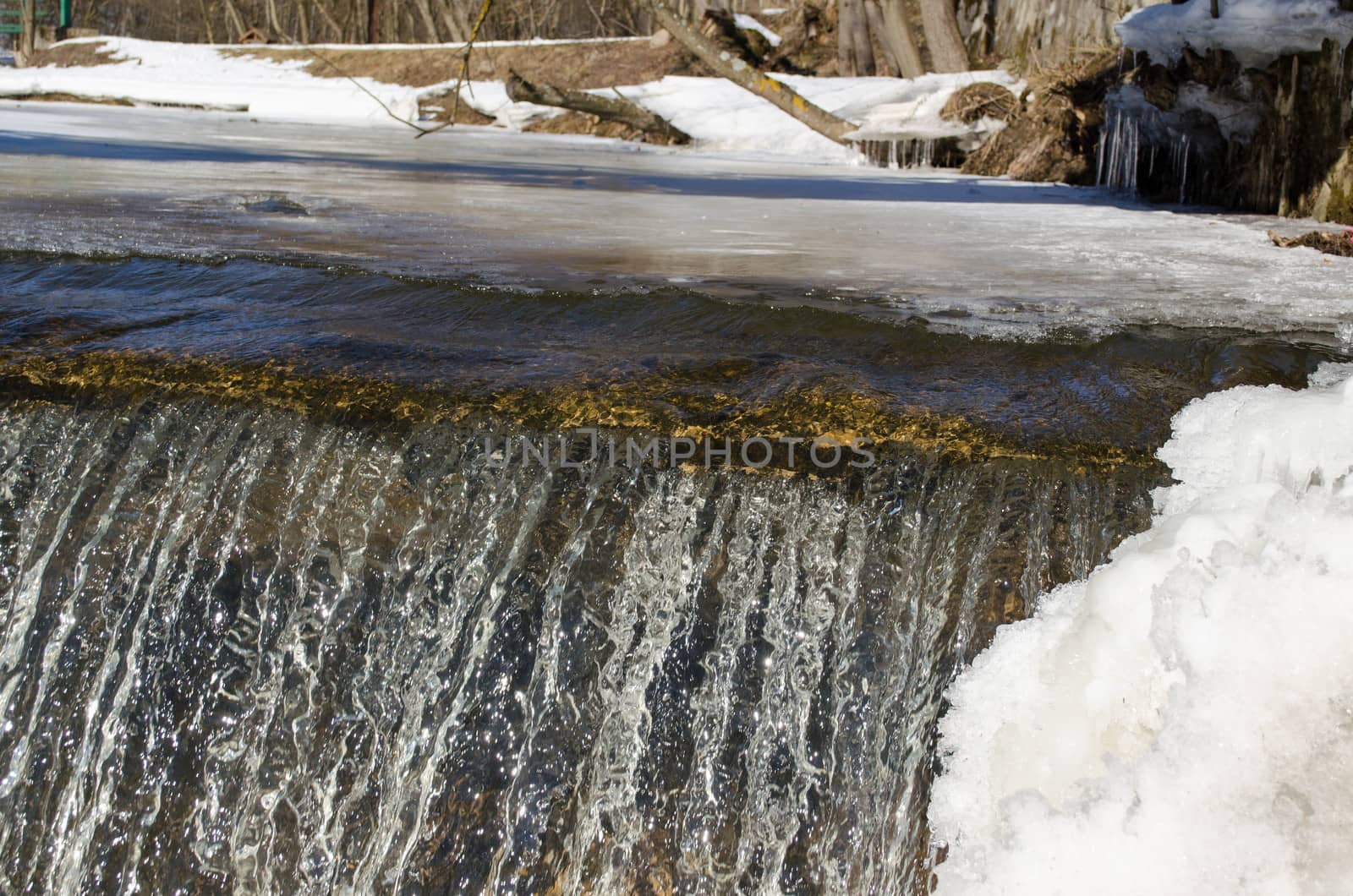 amazing waterfall ice edge and water glance shine reflections of sun in winter.