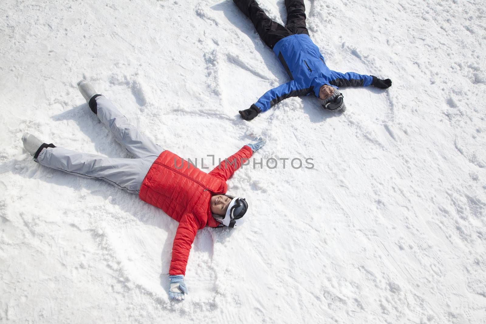 Couple Lying On Snow Making Snow Angel