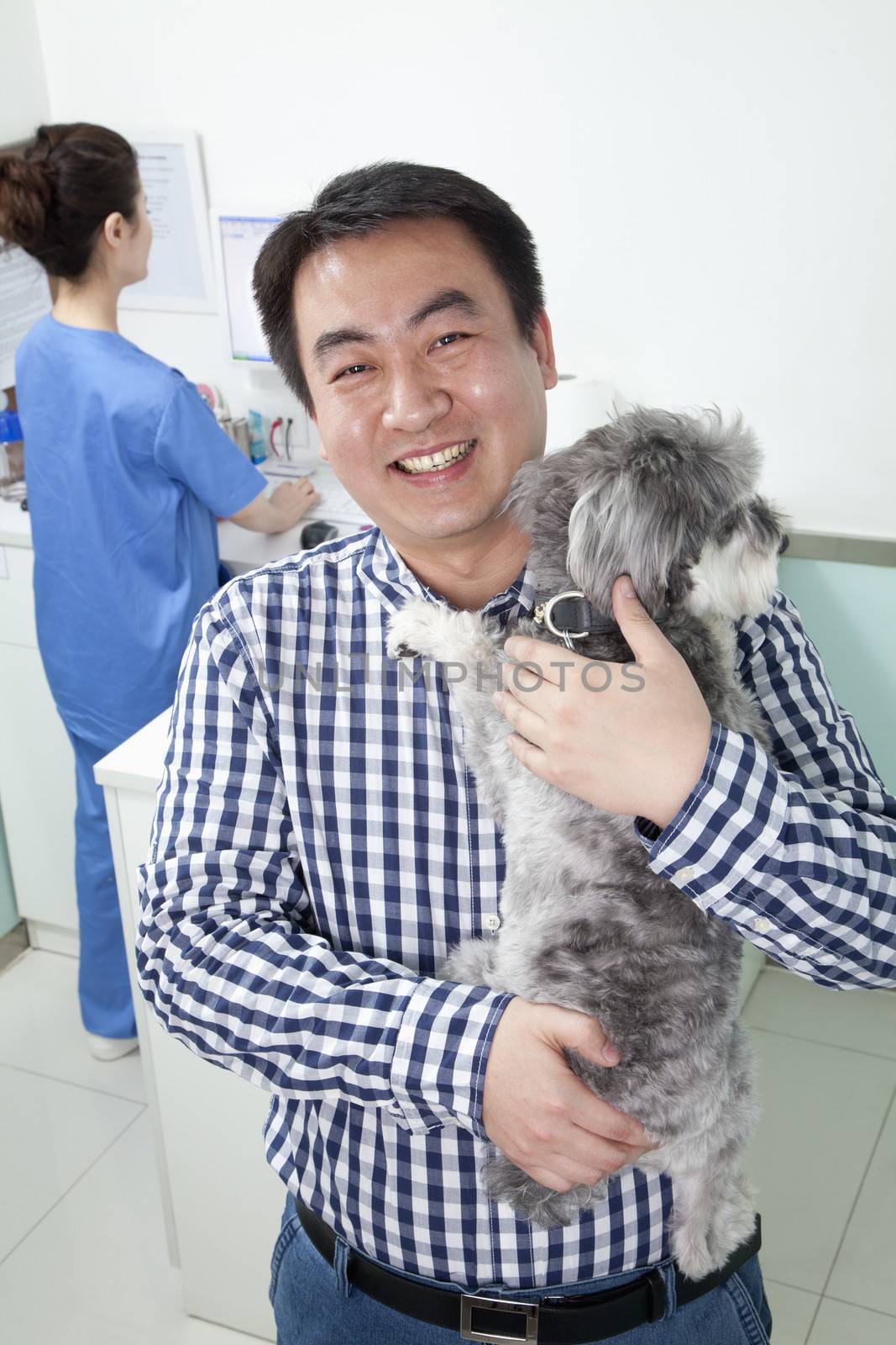 Man with pet dog in veterinarian's office by XiXinXing