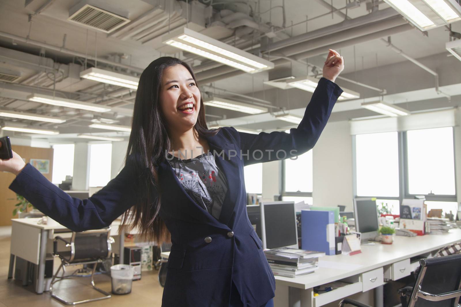 Young businesswoman smiling with arms raised in the office