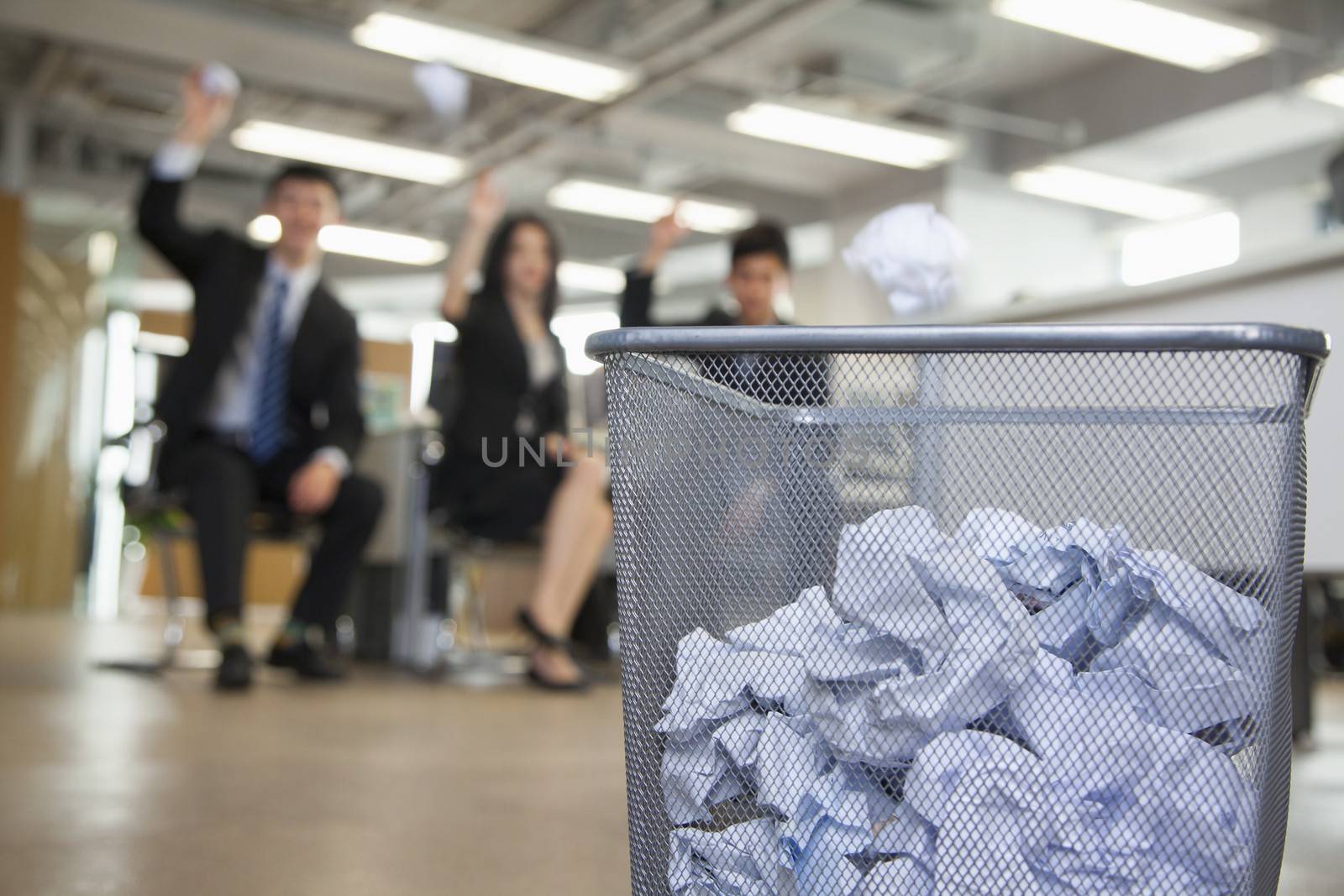 Three coworkers preparing to throw paper into waste basket  by XiXinXing