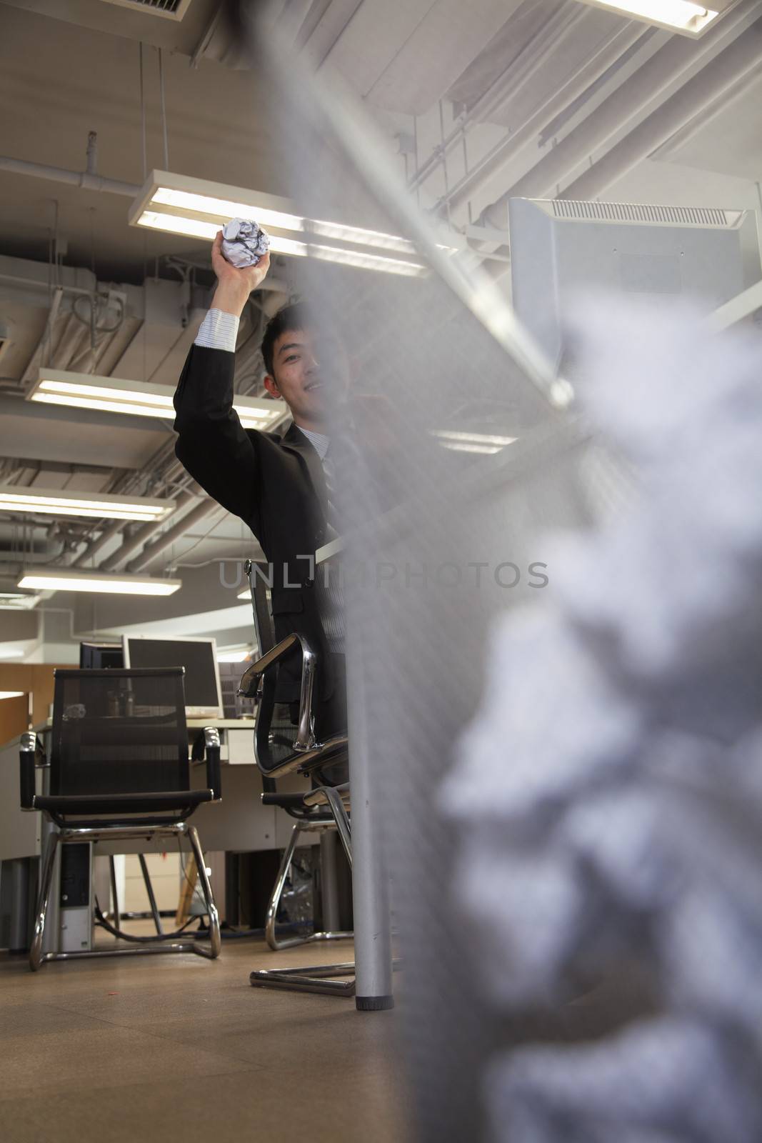 Businessman preparing to throw paper into wastebasket 