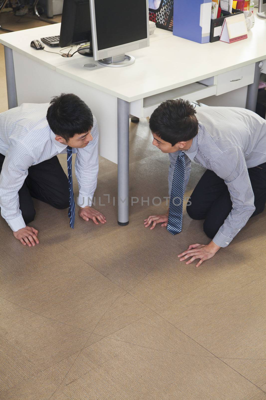 Two businessmen crouching on the floor