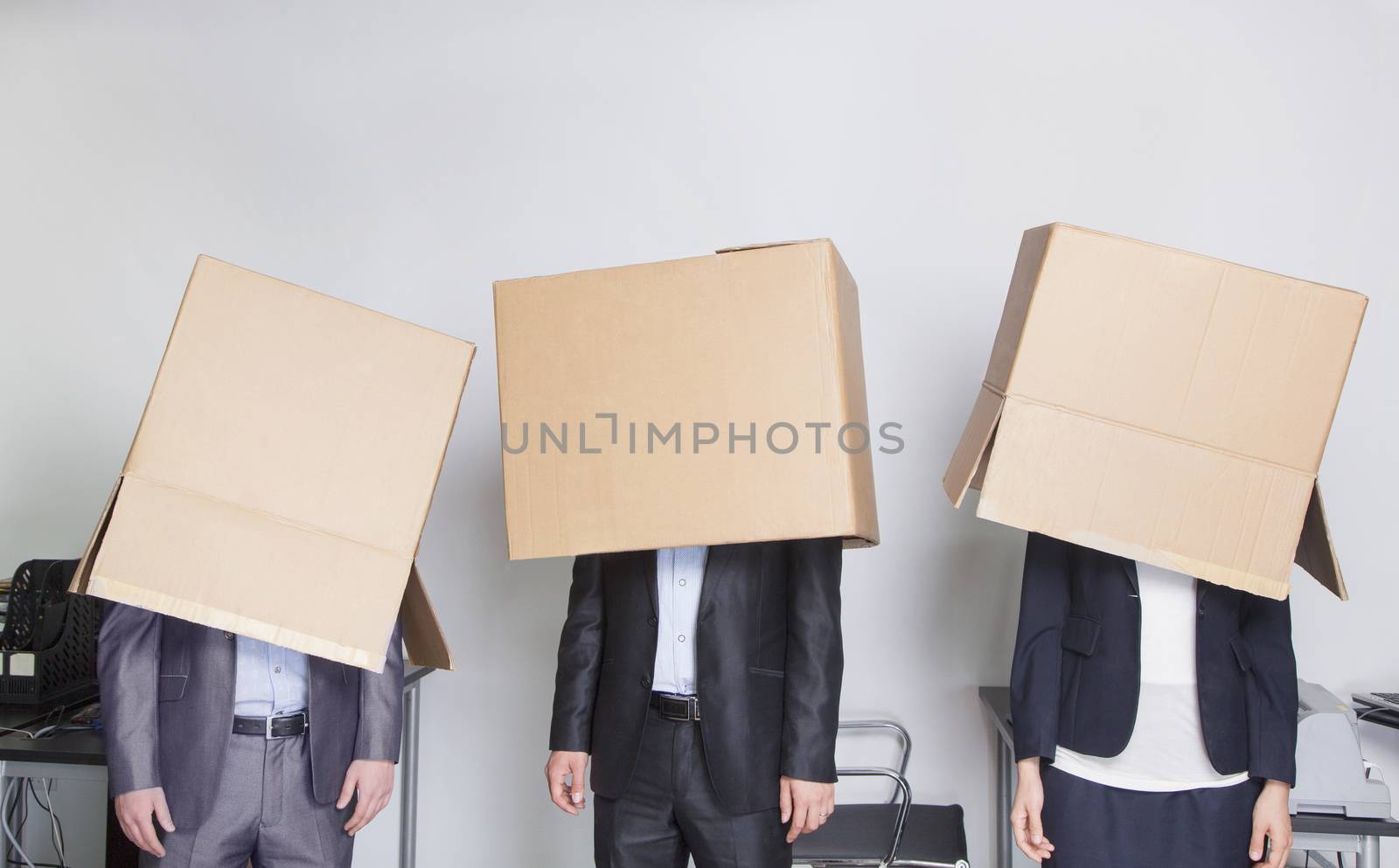 Three business people with boxes over their heads in an office