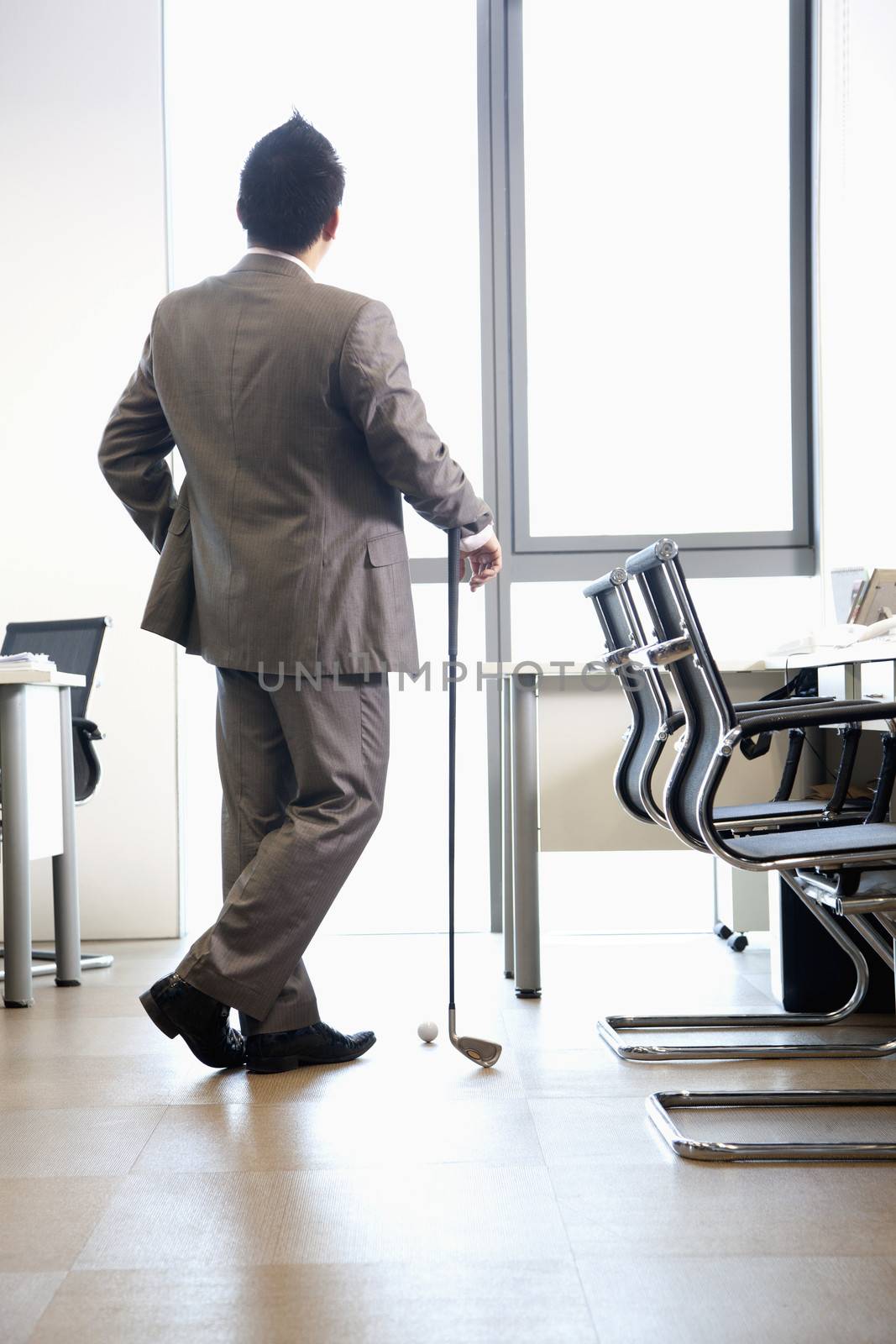 Businessman holding golf club in his office