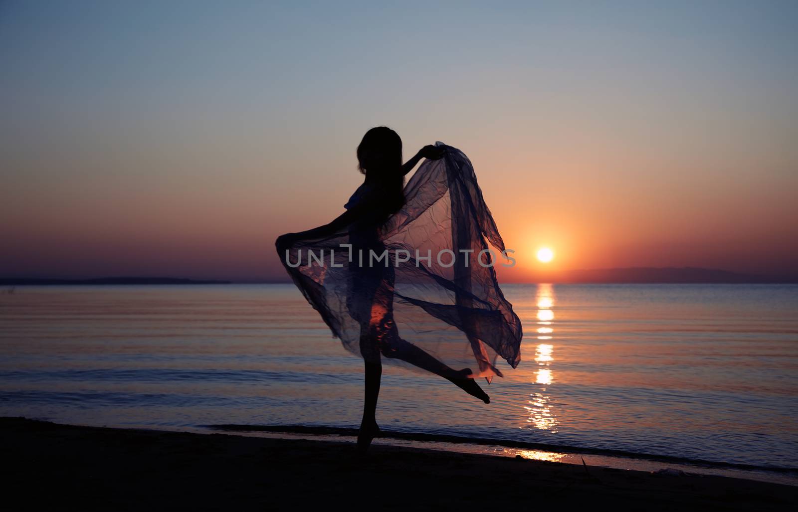 Silhouette of the woman with fiber dancing at the beach during sunset. Natural darkness and colors