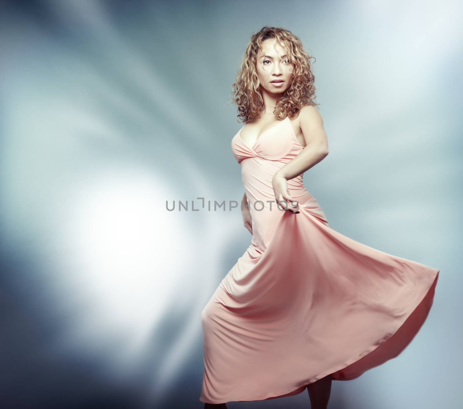 Woman in pink dress dancing on defocused modern background