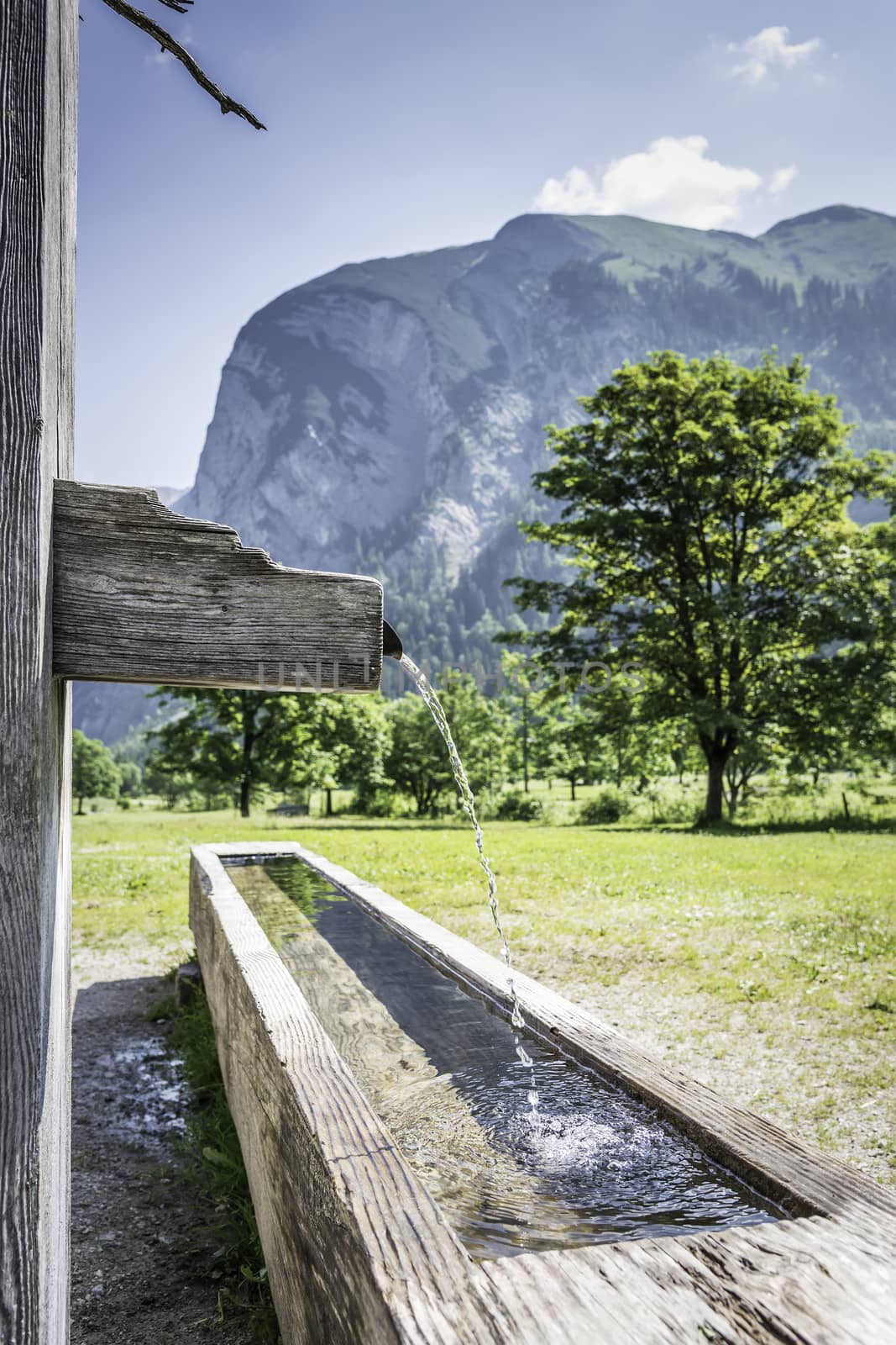 Drink fountain in Alps with mountains by w20er