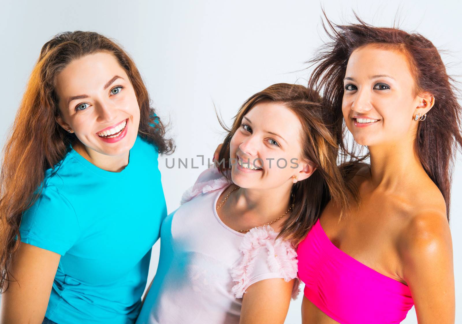 three beautiful teenage girls smiling on light background