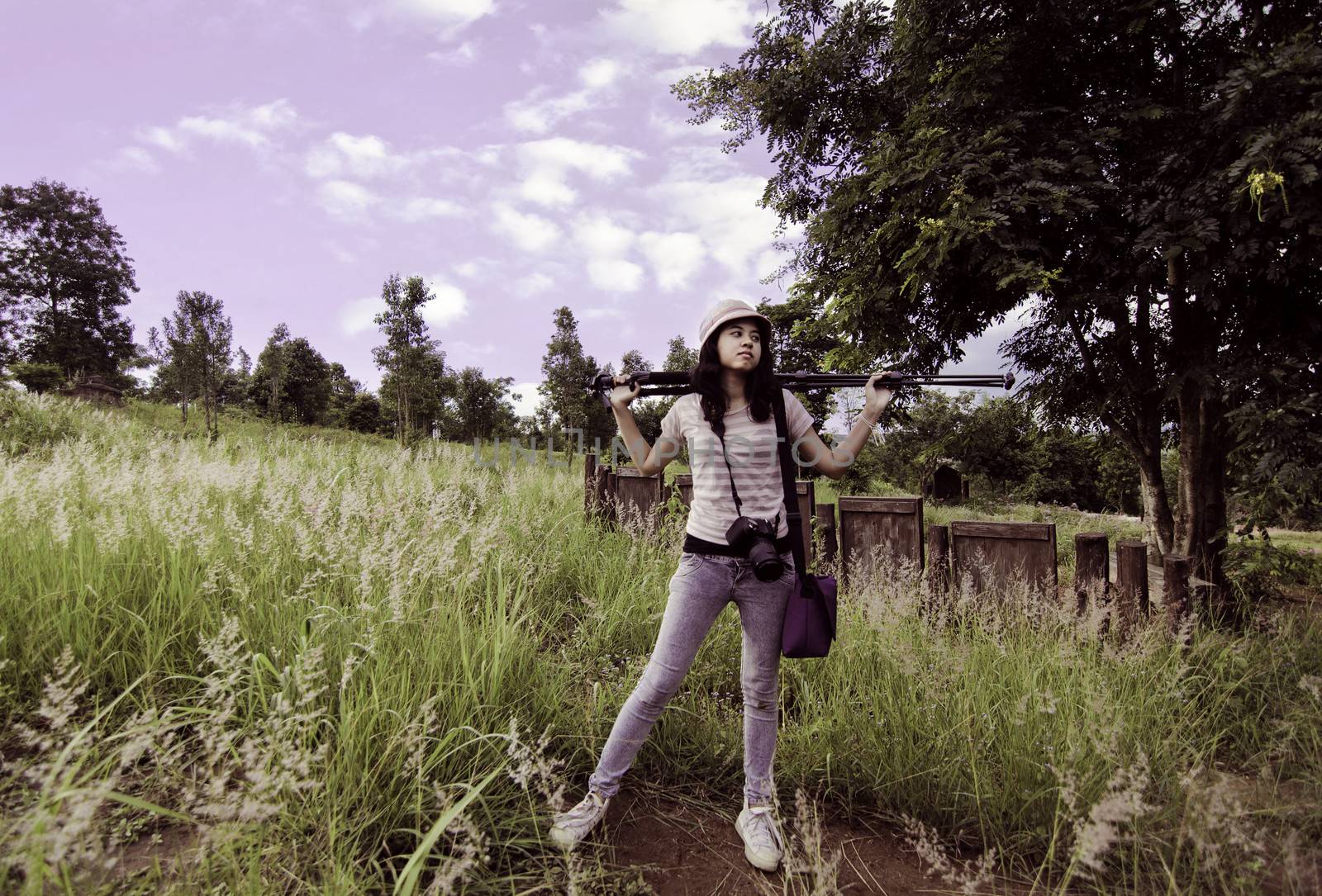 Young photographer carry on tripod in rural field  by siraanamwong