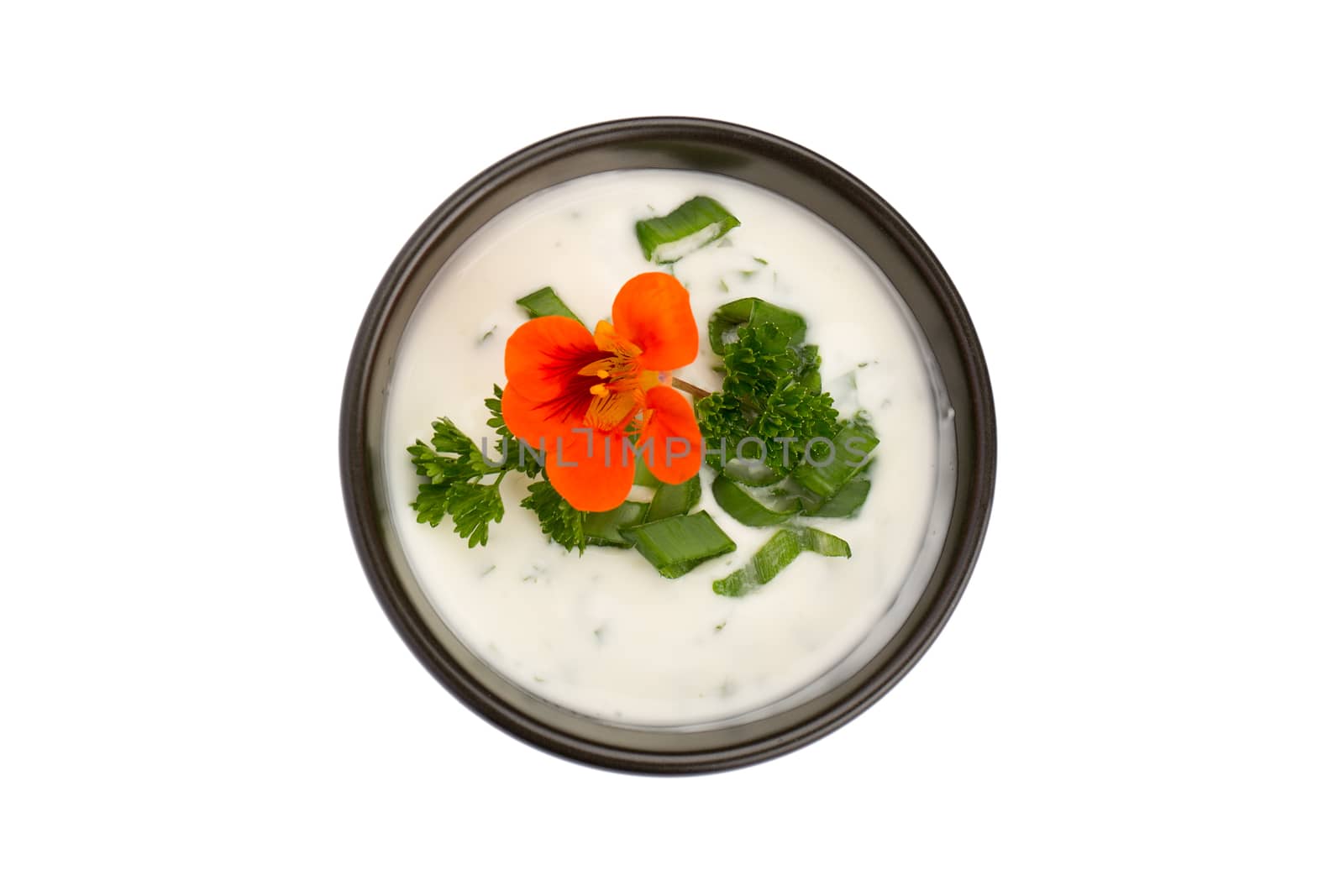 Bowl of white sauce with chives, parsley and orange flower isolated on white background.