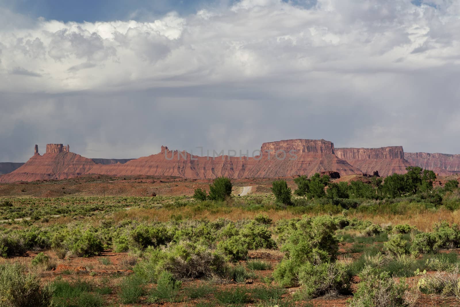 Red sandstone peaks and plateaus of La Sal Mountains with foreground of wild desert. Copy space in blue sky with windswept, white clouds.  La Sal Mountains, south of Moab, Utah, are part of Manti-La Sal National Forest.  With heights of nearly 13,000 feet, the alpine LaSal Mountains are an outdoor recreational and tourist attraction.   