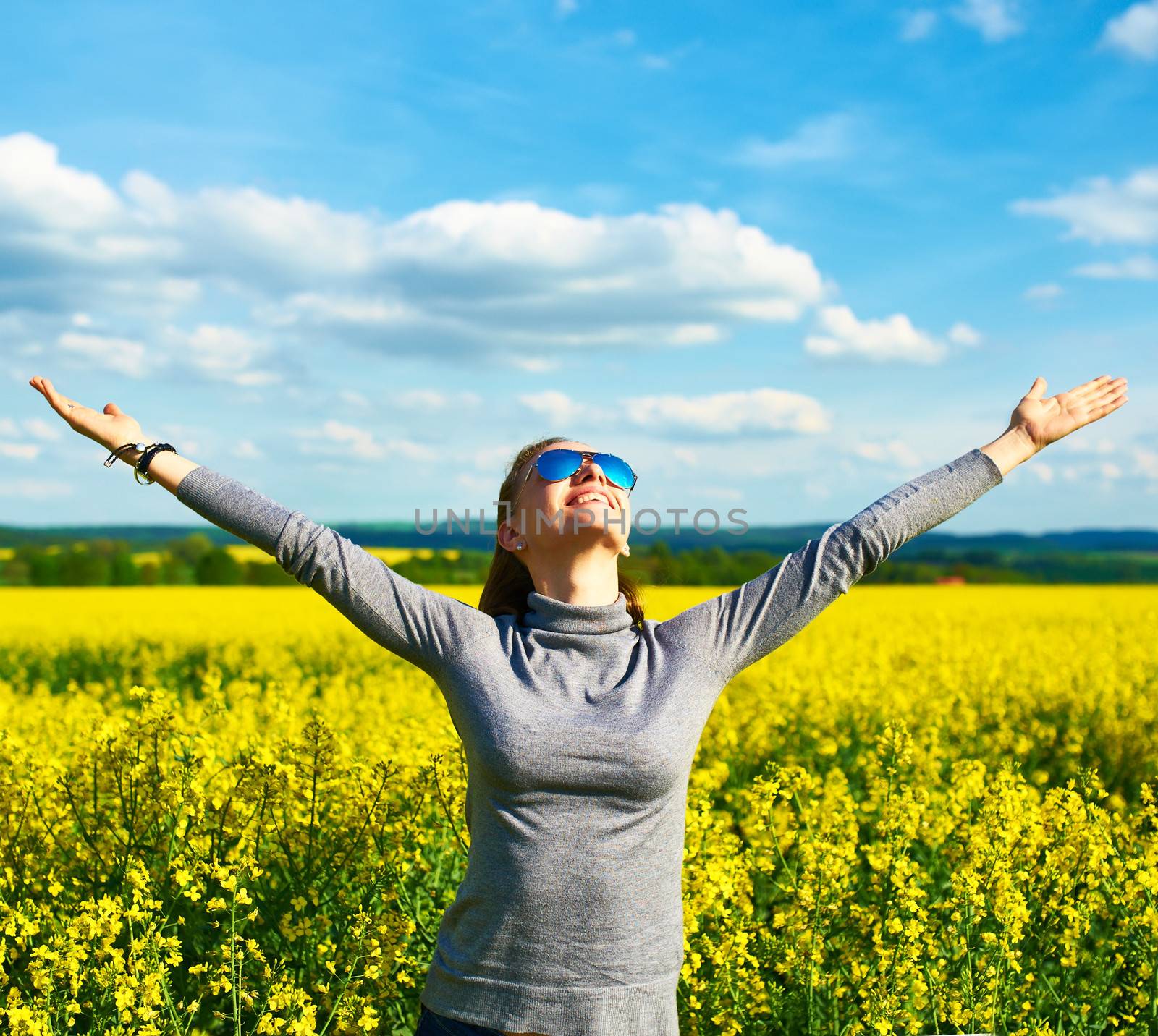 Girl with outstretched arms at colza field