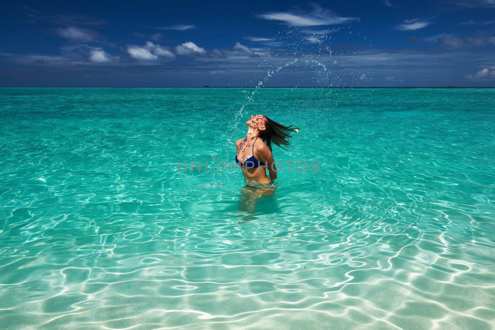 Woman splashing water with her hair in the ocean