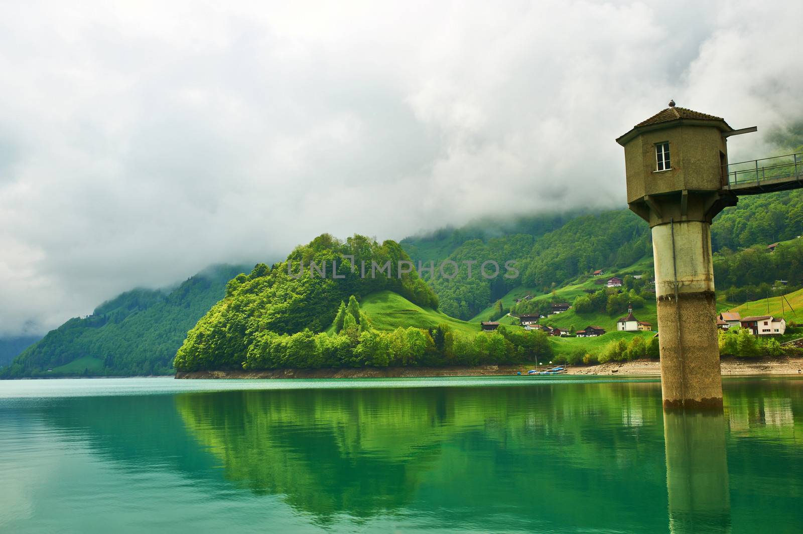 Beautiful emerald mountain lake in Switzerland under low clouds