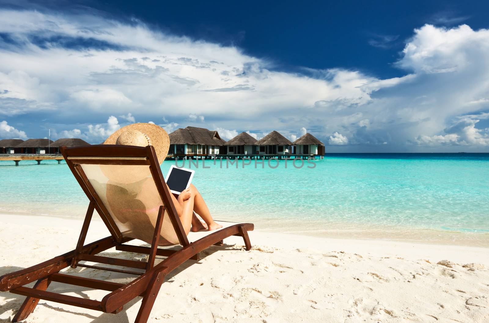 Young woman in hat with tablet pc at the beach