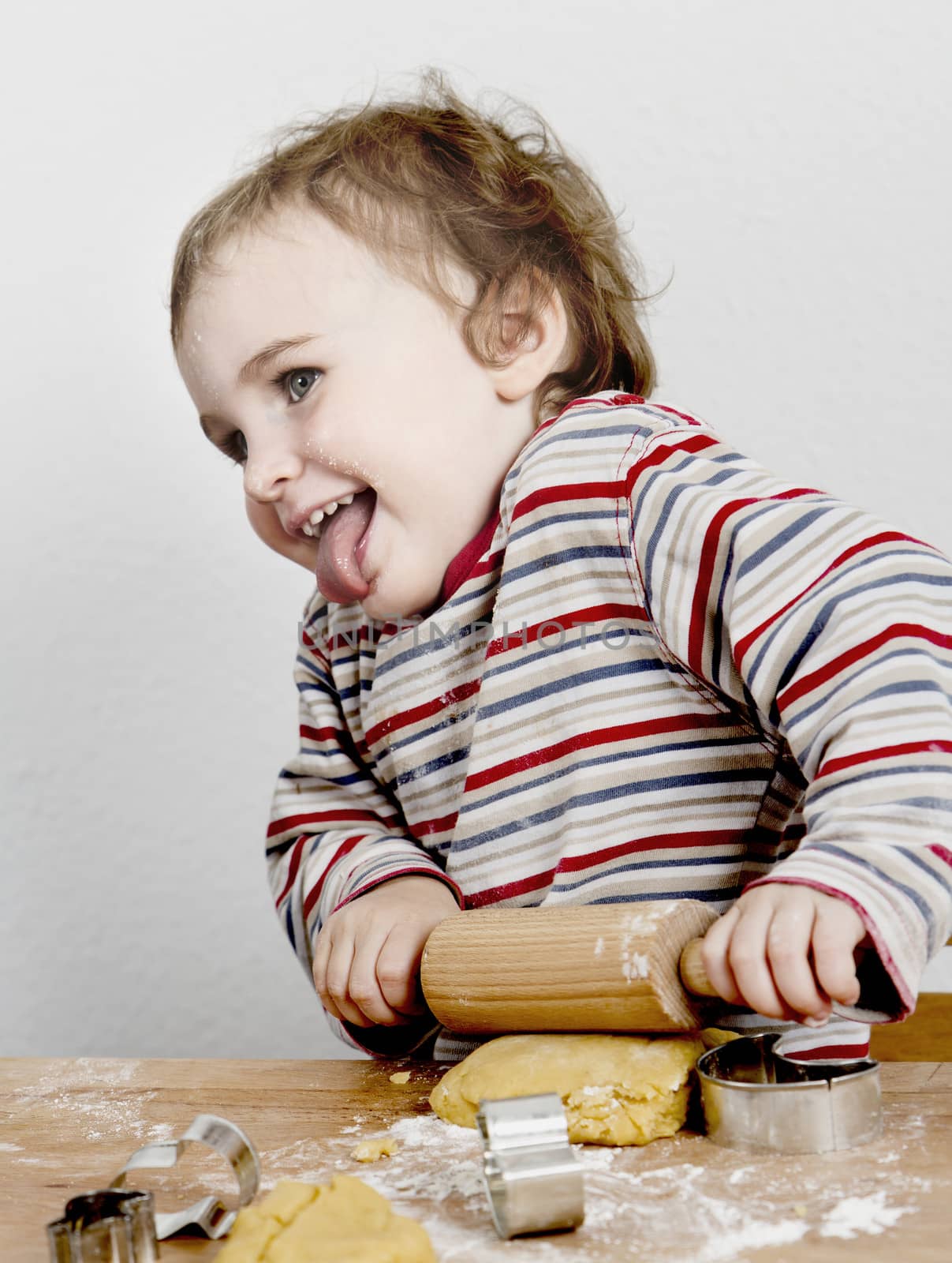 happy young child with rolling pin in grey background by gewoldi
