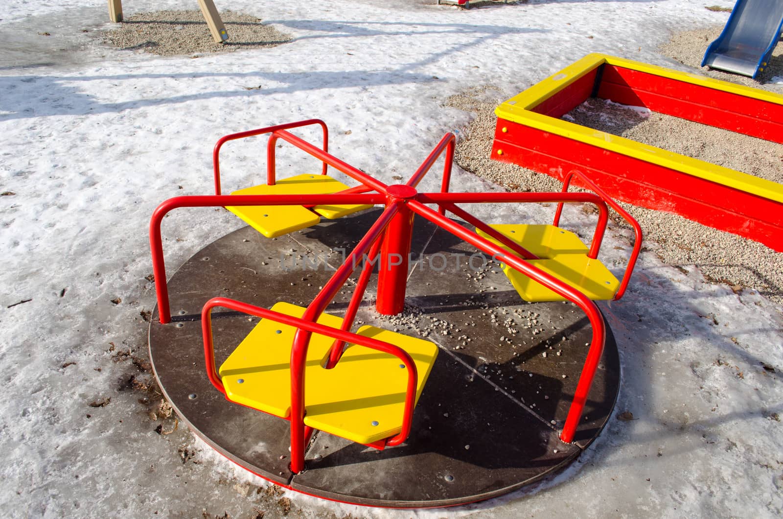 playgrounds carousel with yellow chairs and red rails in winter