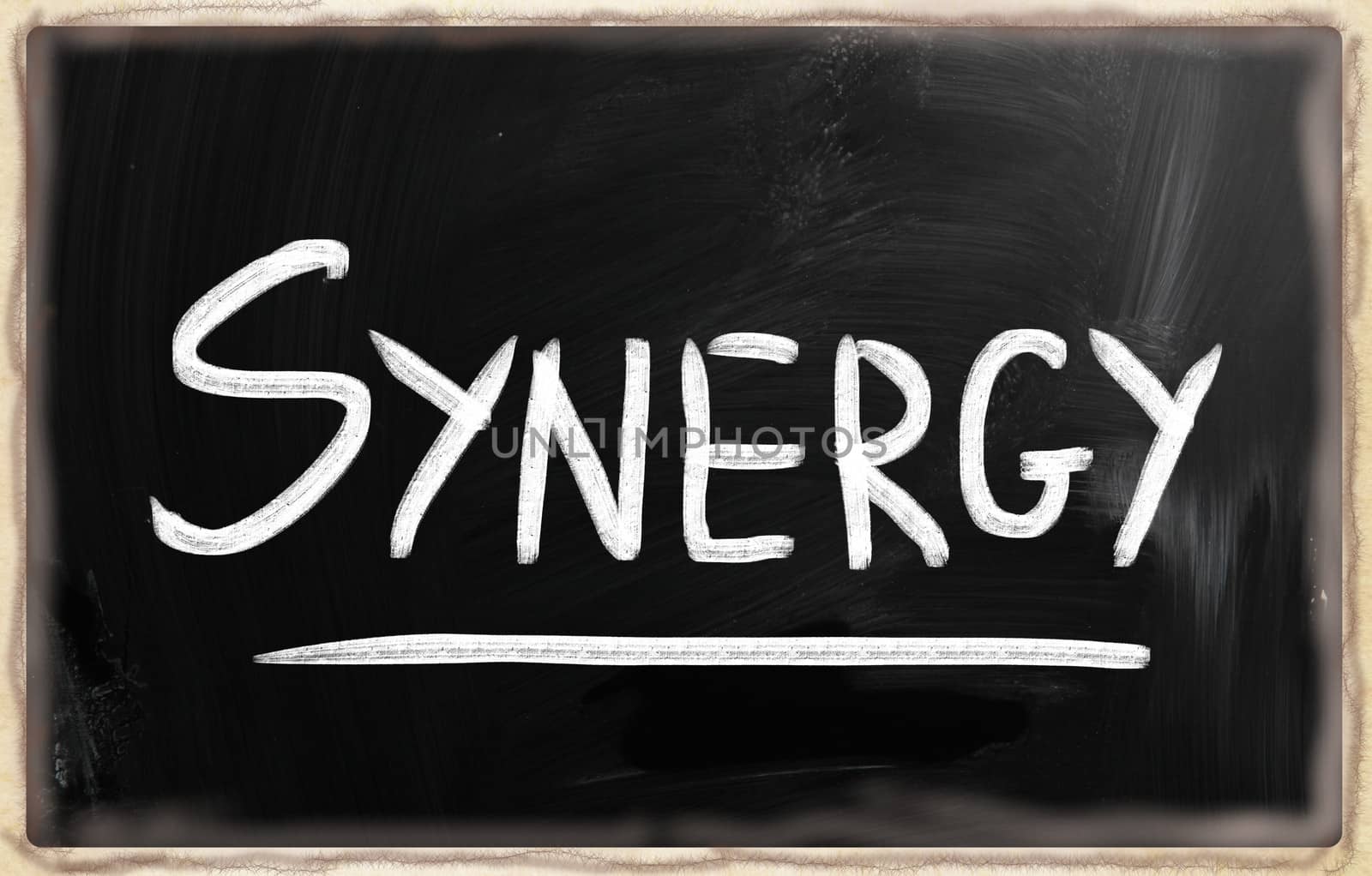 The word "Synergy" handwritten with white chalk on a blackboard