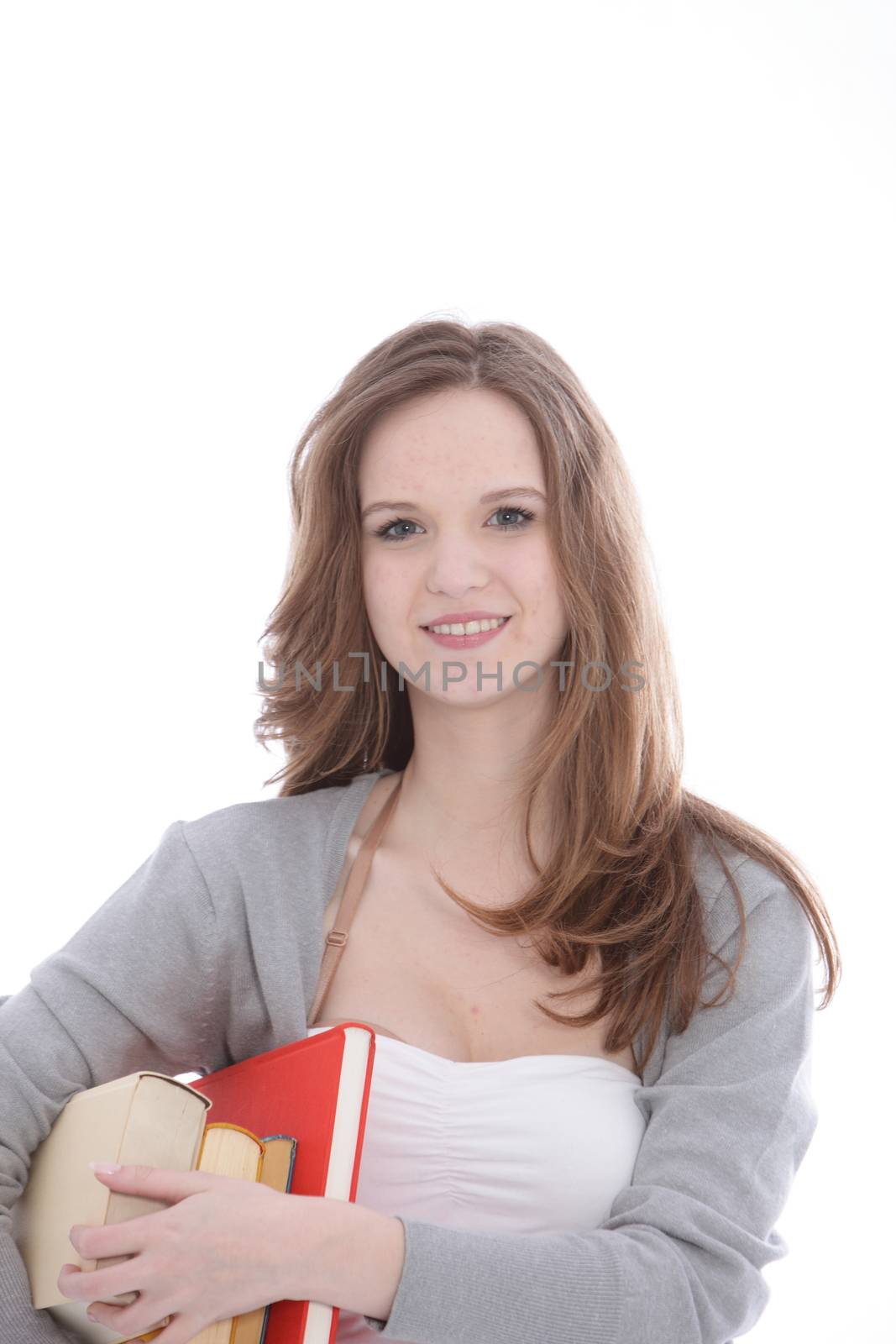 Pretty young teenage student with textbooks held under her arm standing smiling at the camera isolated on white