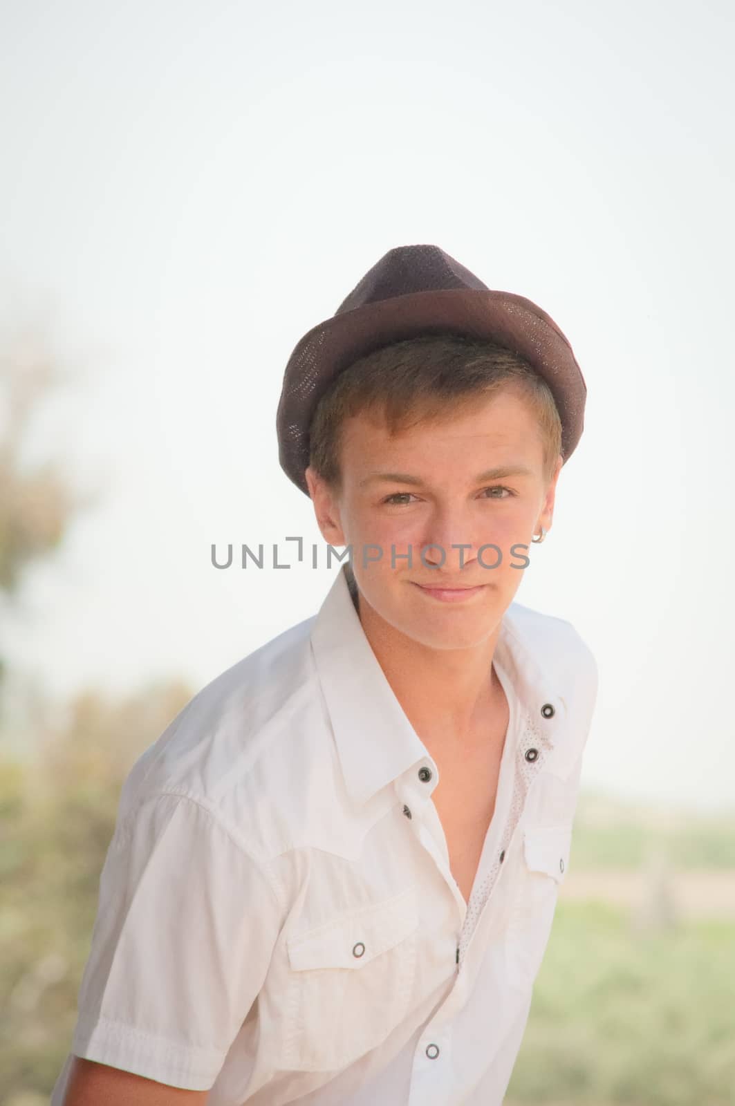 Portrait of a teenager in a white shirt and a brown hat.