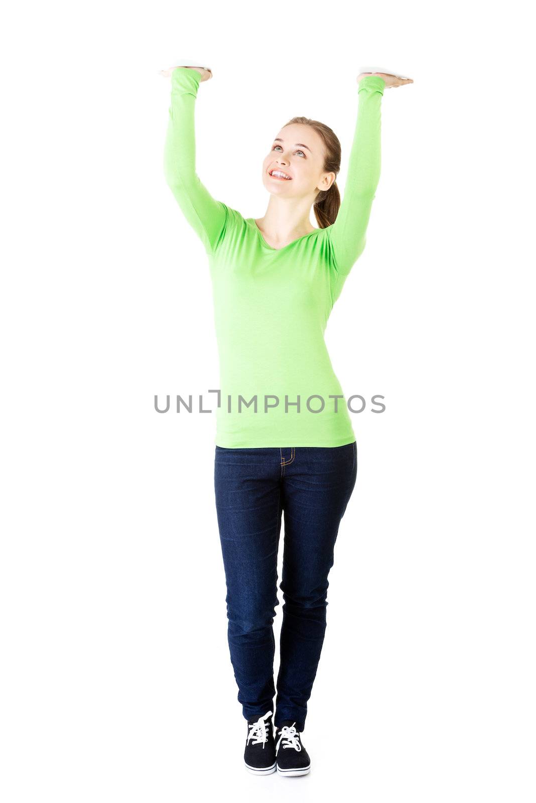 Smiling young woman is holding something abstract above her head by BDS