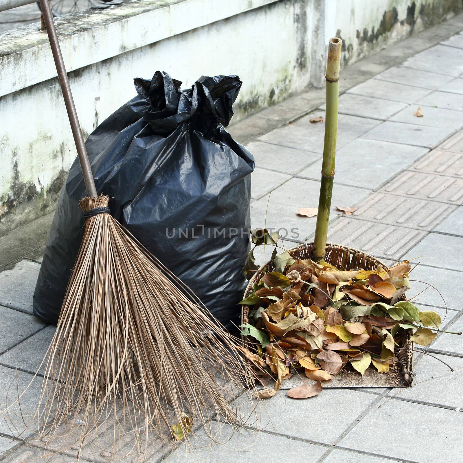 Dry leaves, broom, waste scoop and Garbage bags on footpath