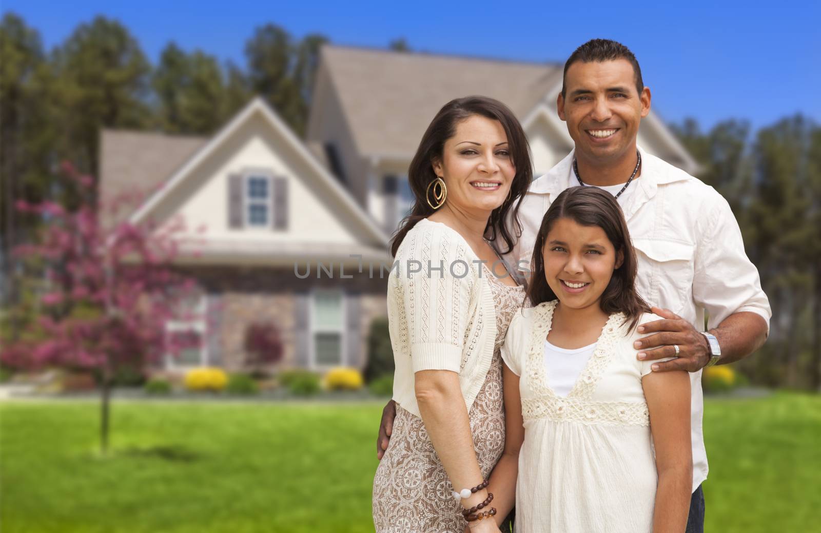 Happy Hispanic Mother, Father and Daughter in Front of Their Home.