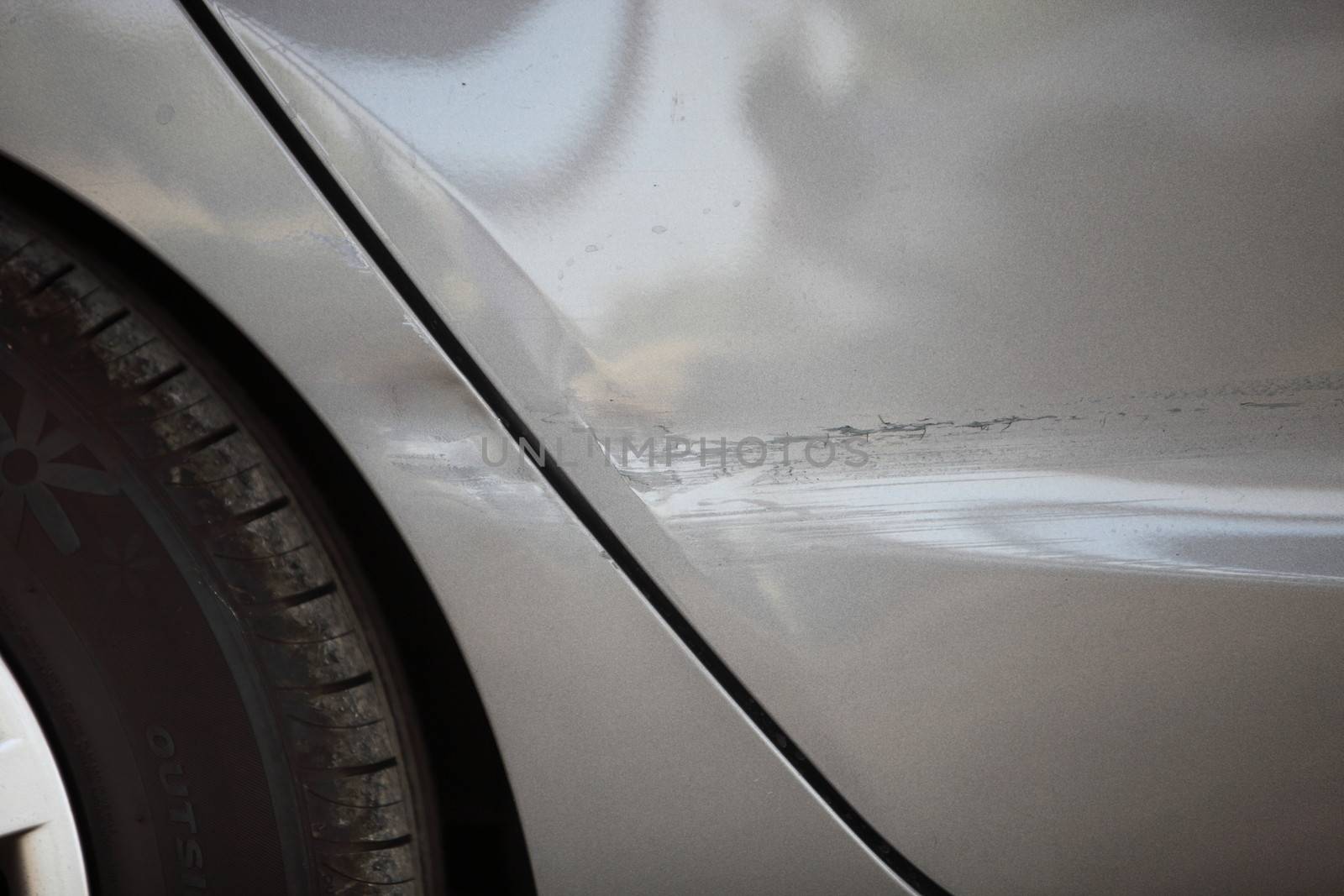 Closeup partial view of the side panel and wheel hub of a white car