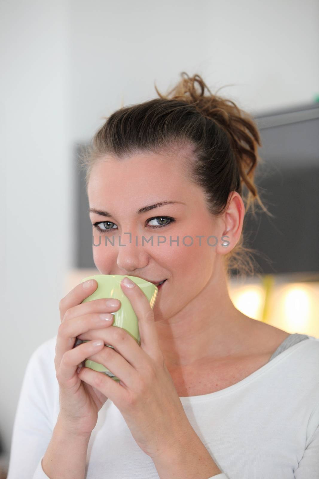 Portrait of a a pretty young woman drinking a mug of coffee indoors while taking a break