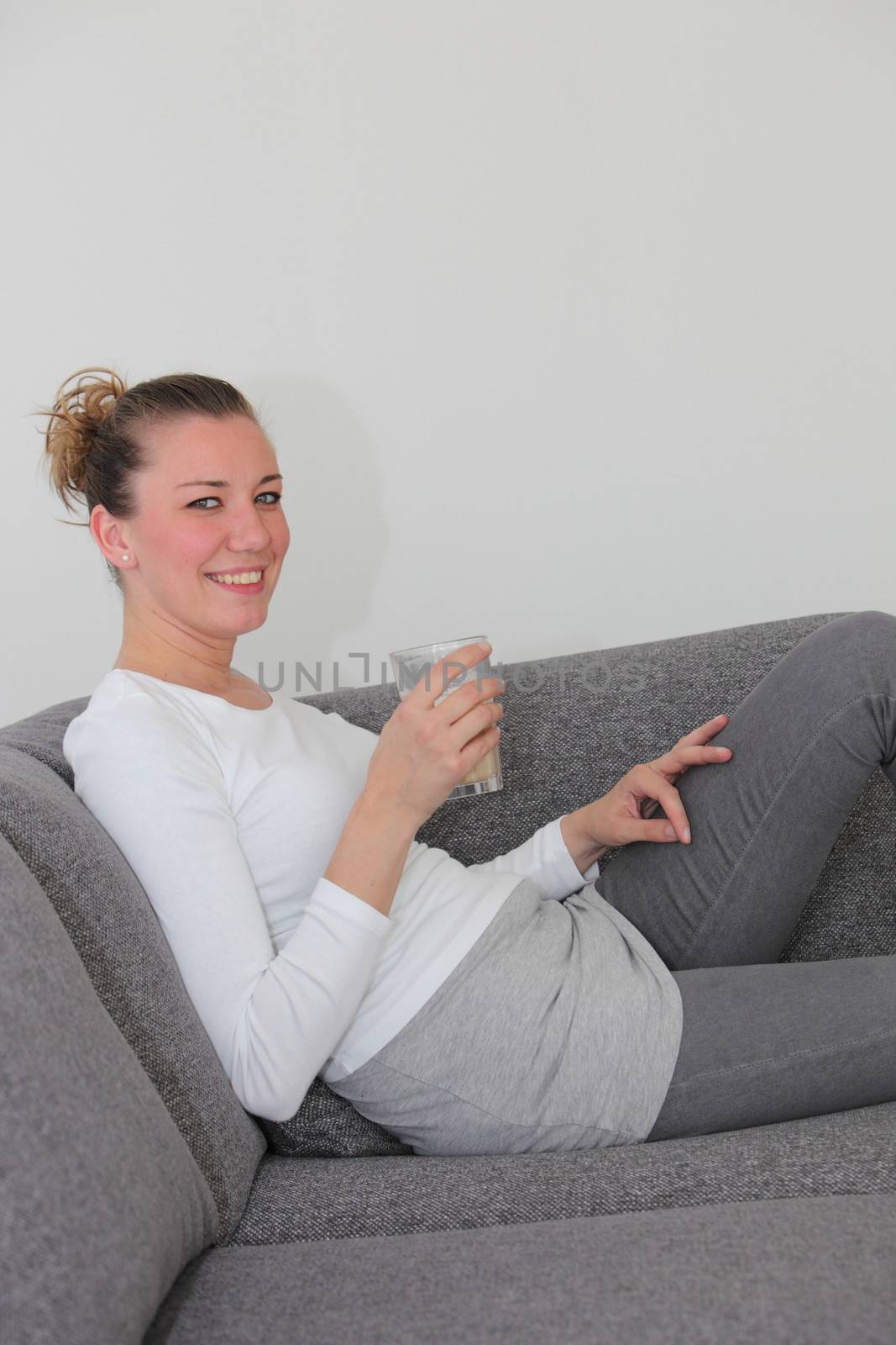 Attractive woman relaxing on a sofa at home by Farina6000