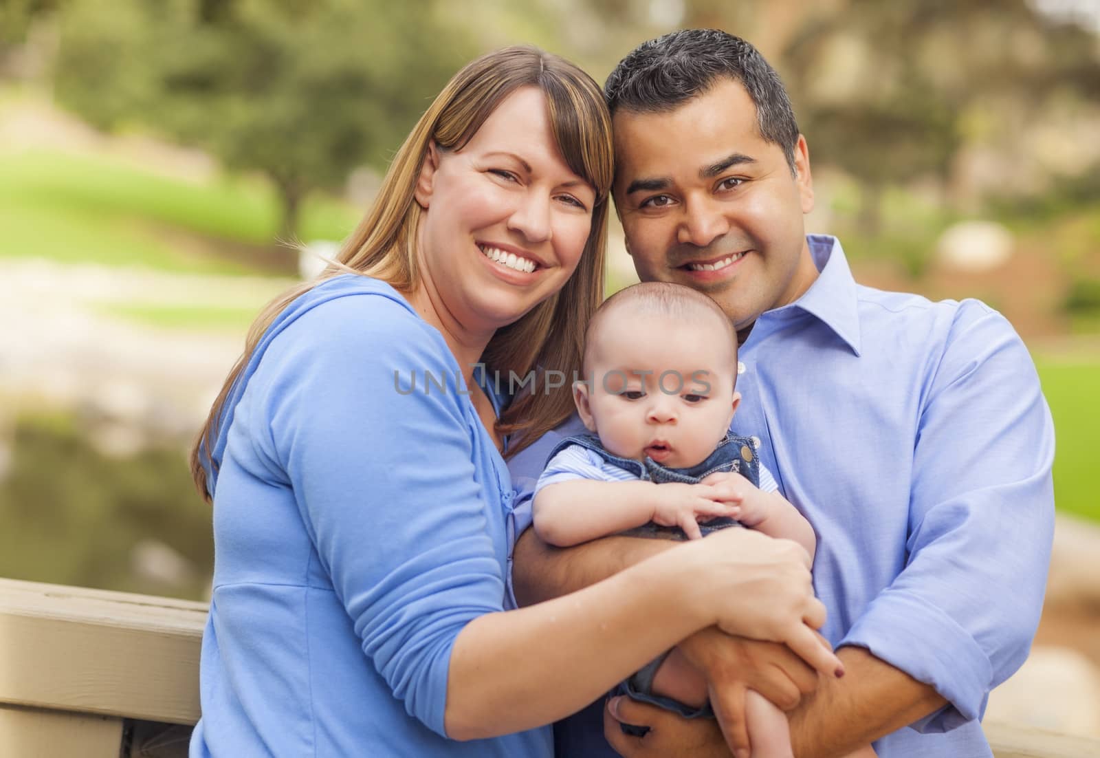 Attractive Happy Mixed Race Young Family Posing for A Portrait Outside in the Park.