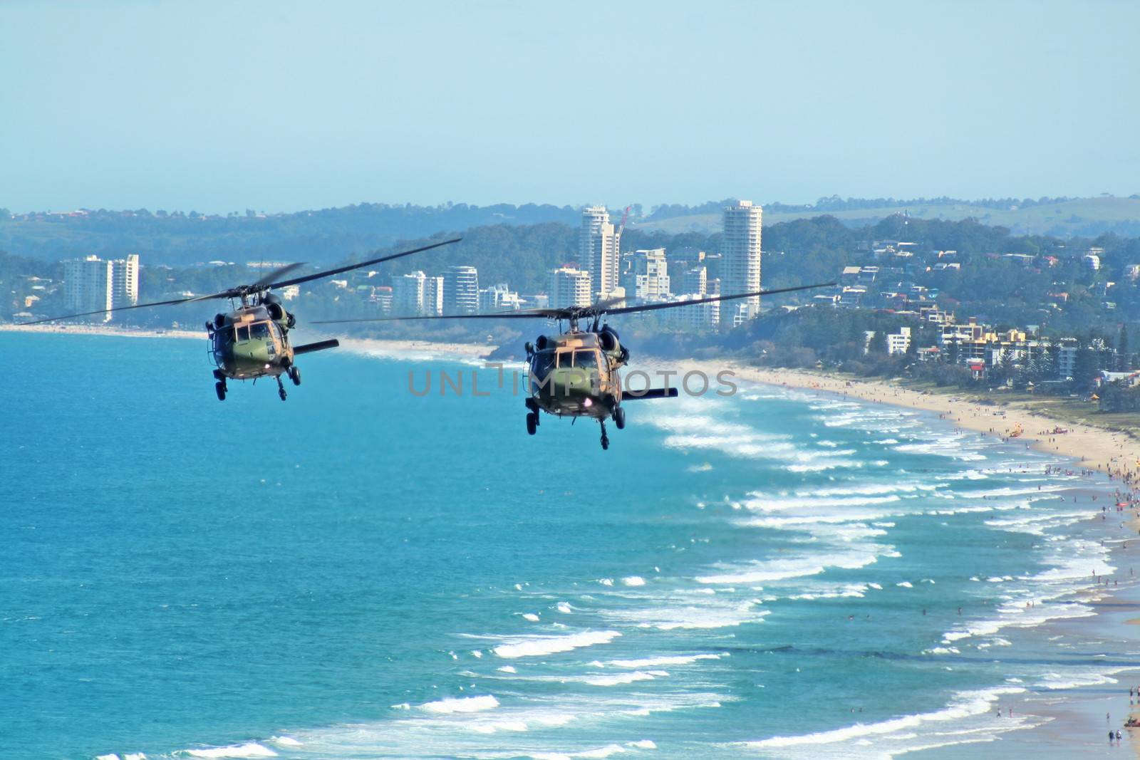 Australian Army Black choppers fly North across Surfers Paradise and Gold Coast beaches Australia.