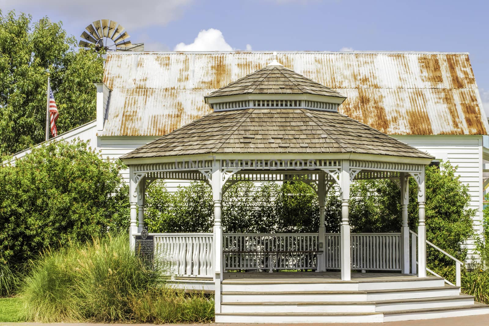 Gazebo set in the country with an old barn behind it.