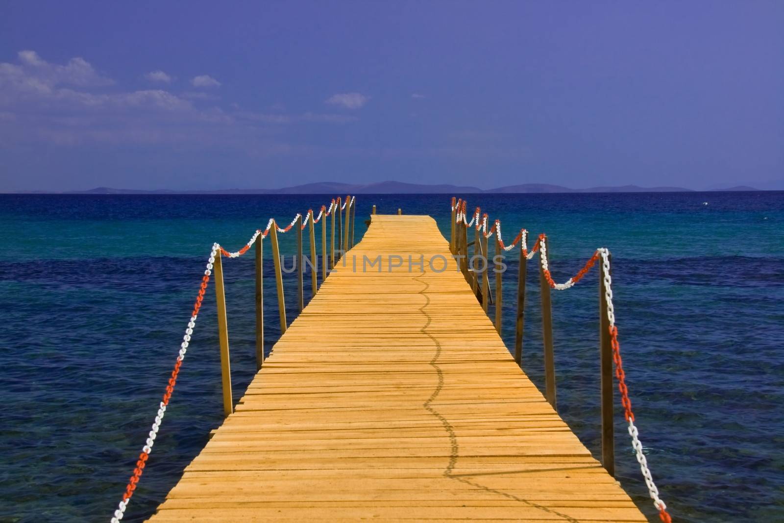 wooden peer on blue sea with blue sky 