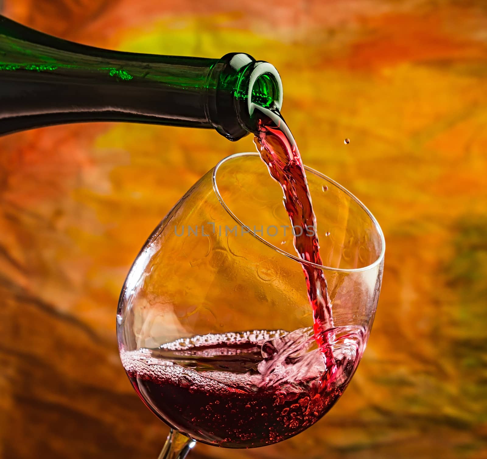 Wine pours into the glass of the bottle on a colored background