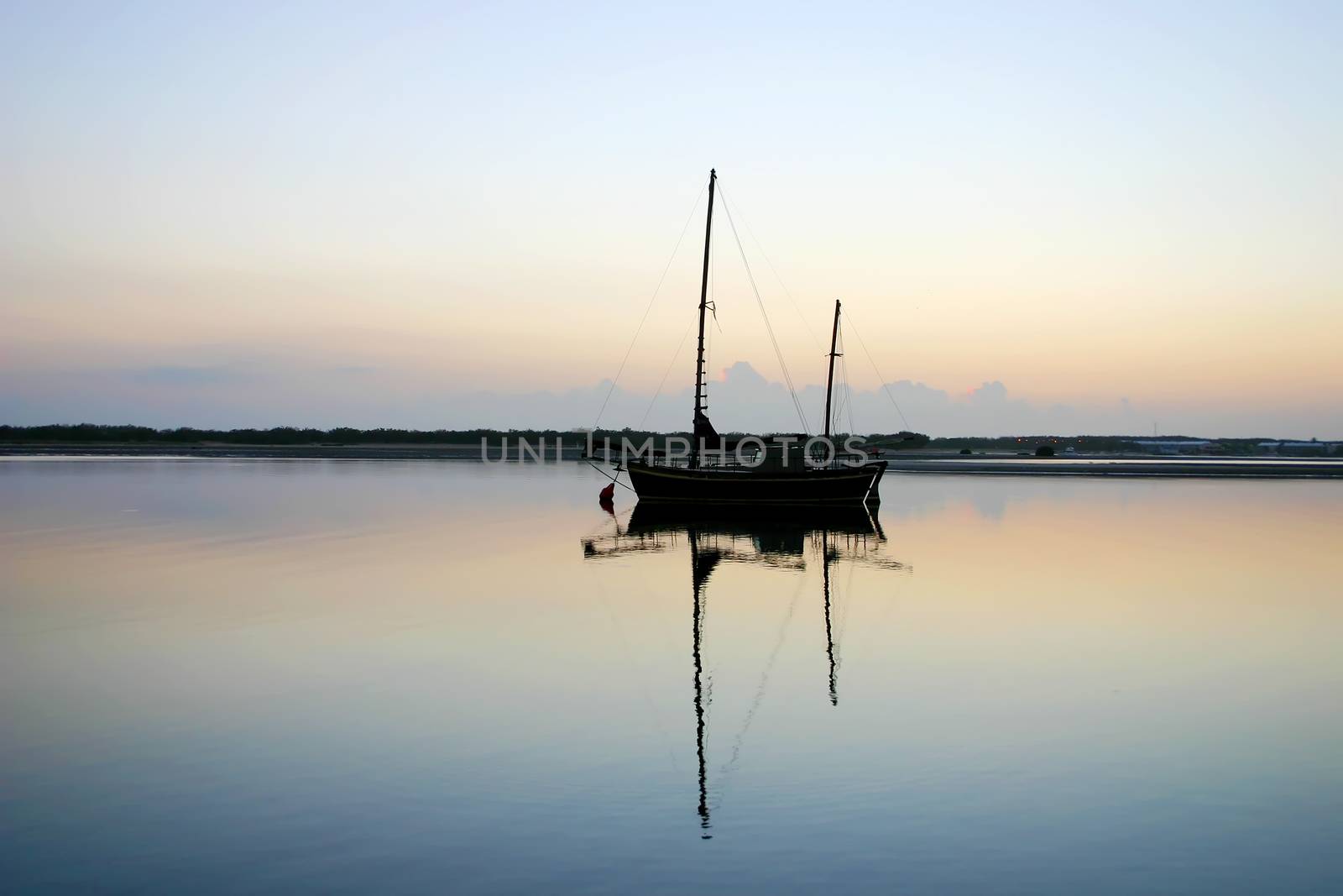 Old vintage ketch moored in a lagoon just before dawn.
