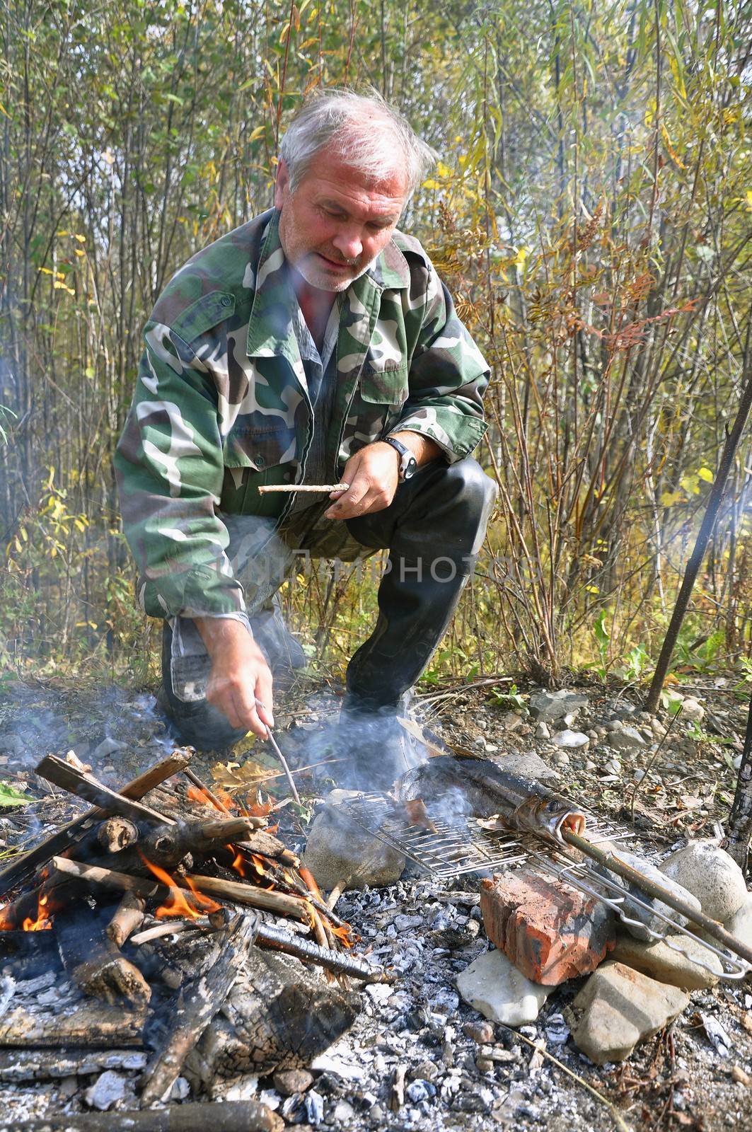 fisherman by the fire roasting fresh fish