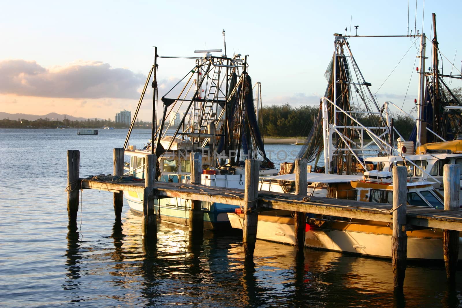 Jetty with trawlers bathed in the golden light of sunset.