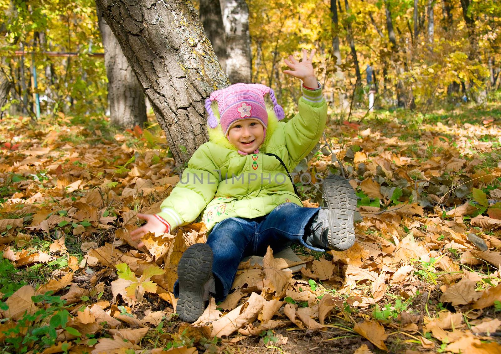 girl sits under tree in autumn park