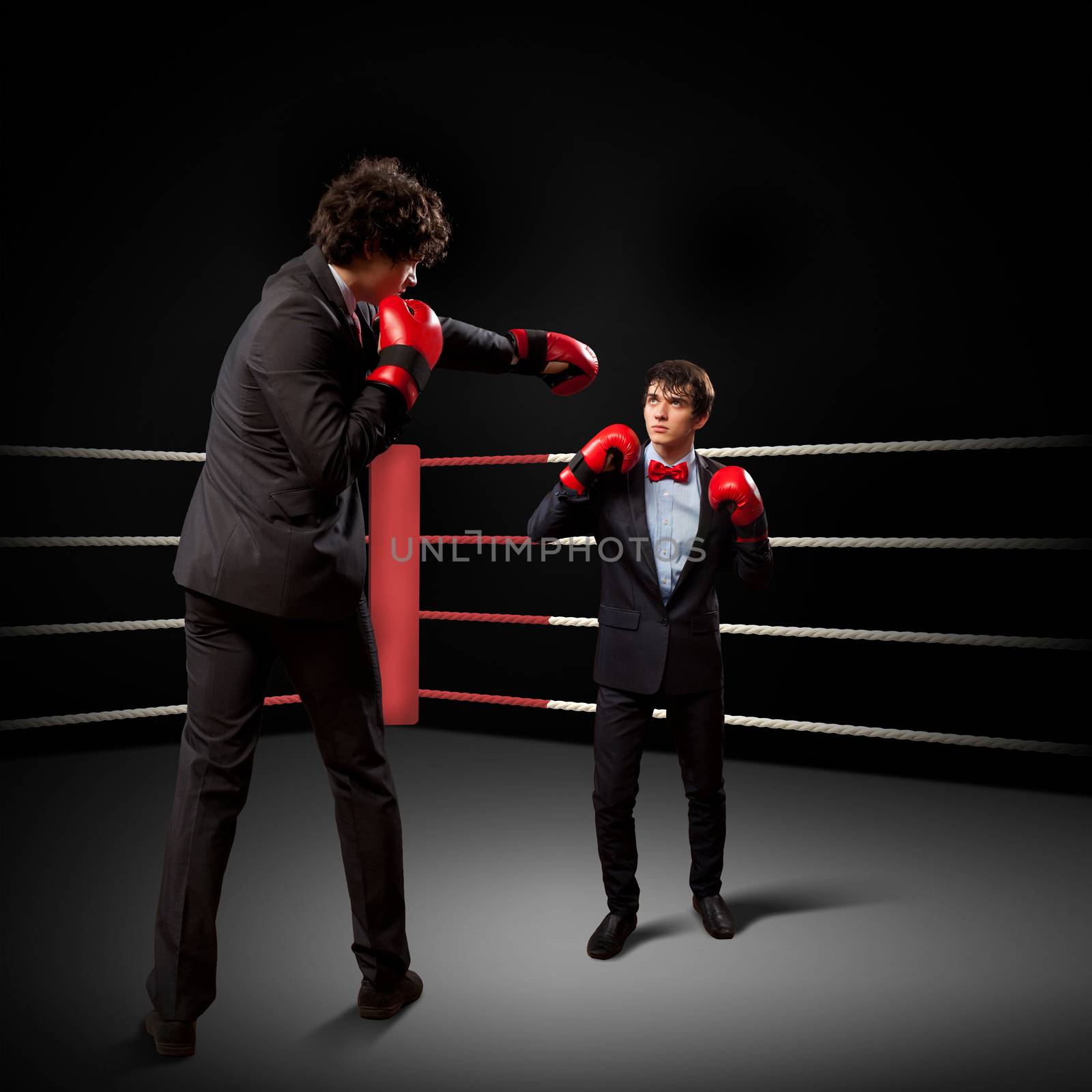 Two young businessman boxing againts dark background . conceptual collage