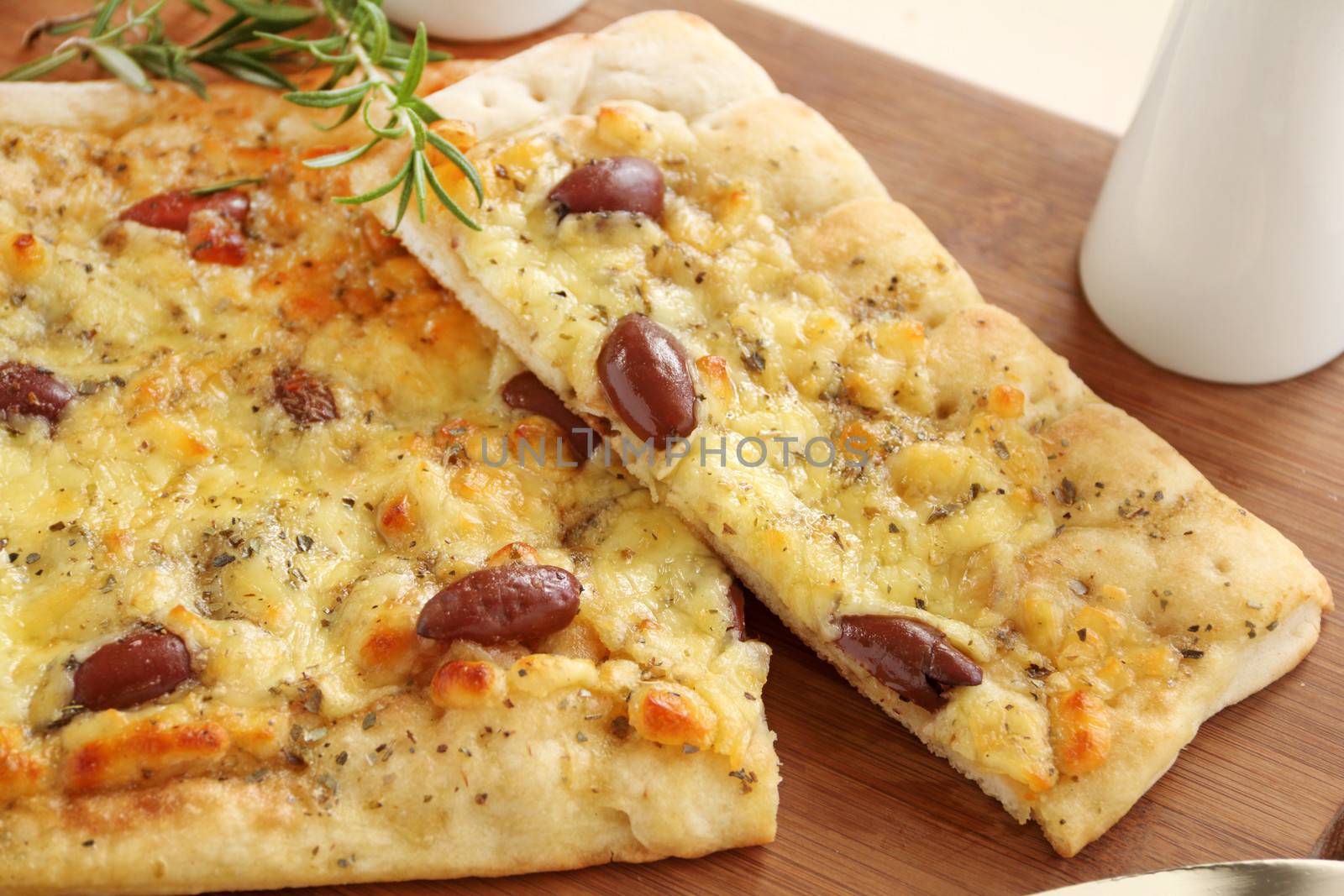 Rectangular gourmet pizza with cheese and olives ready to serve.