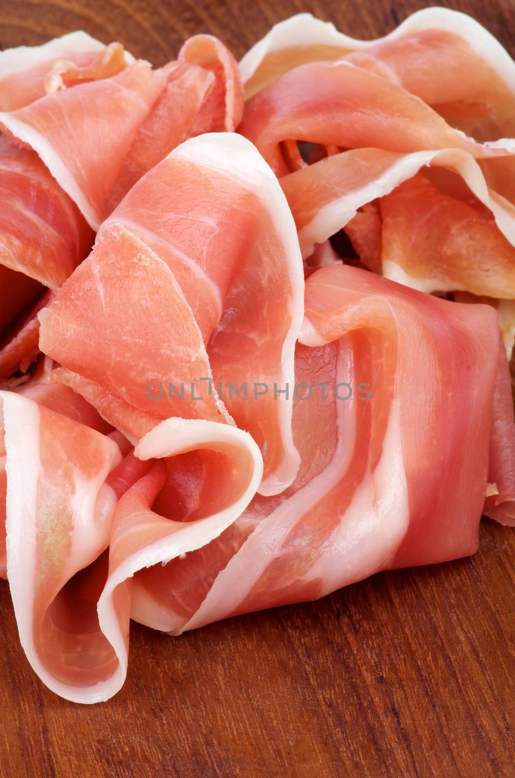 Slices of Delicious Jamon closeup on Wooden background