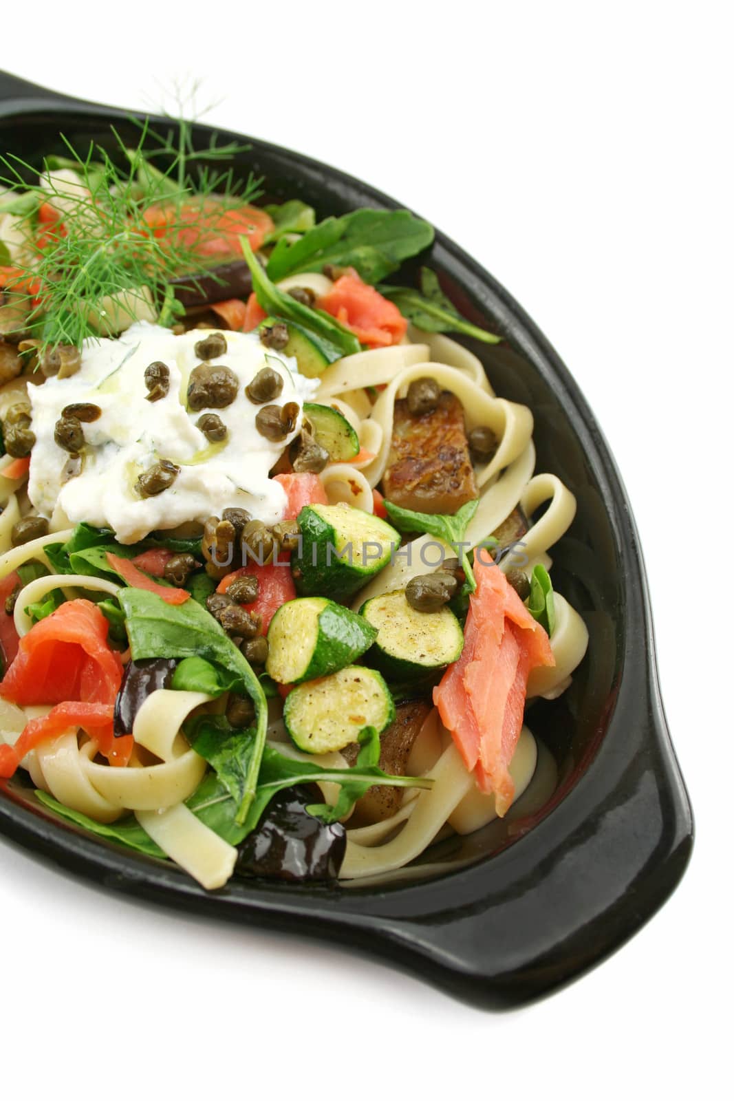 Dish of salmon fettucini with aubergine, zucchini with ricotta, dill and capers.