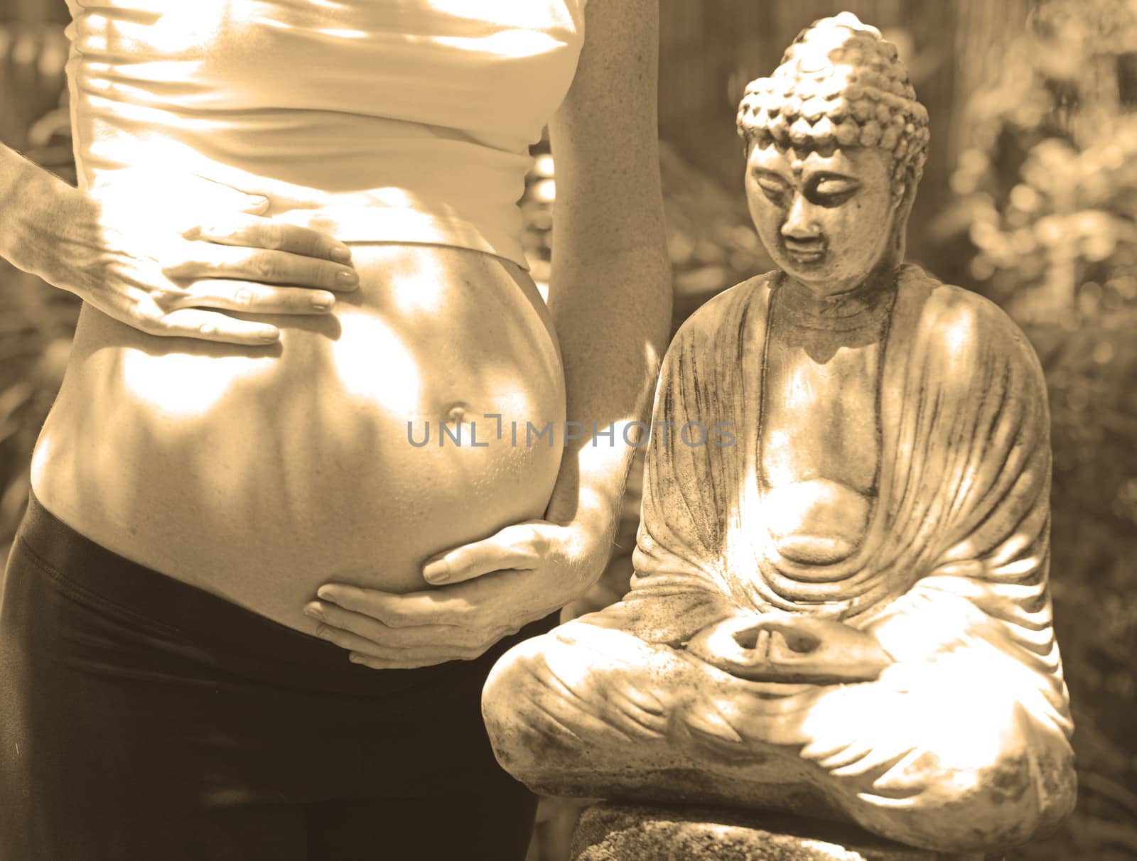 zen pregnancy with pregnant woman standing next to meditation buddha