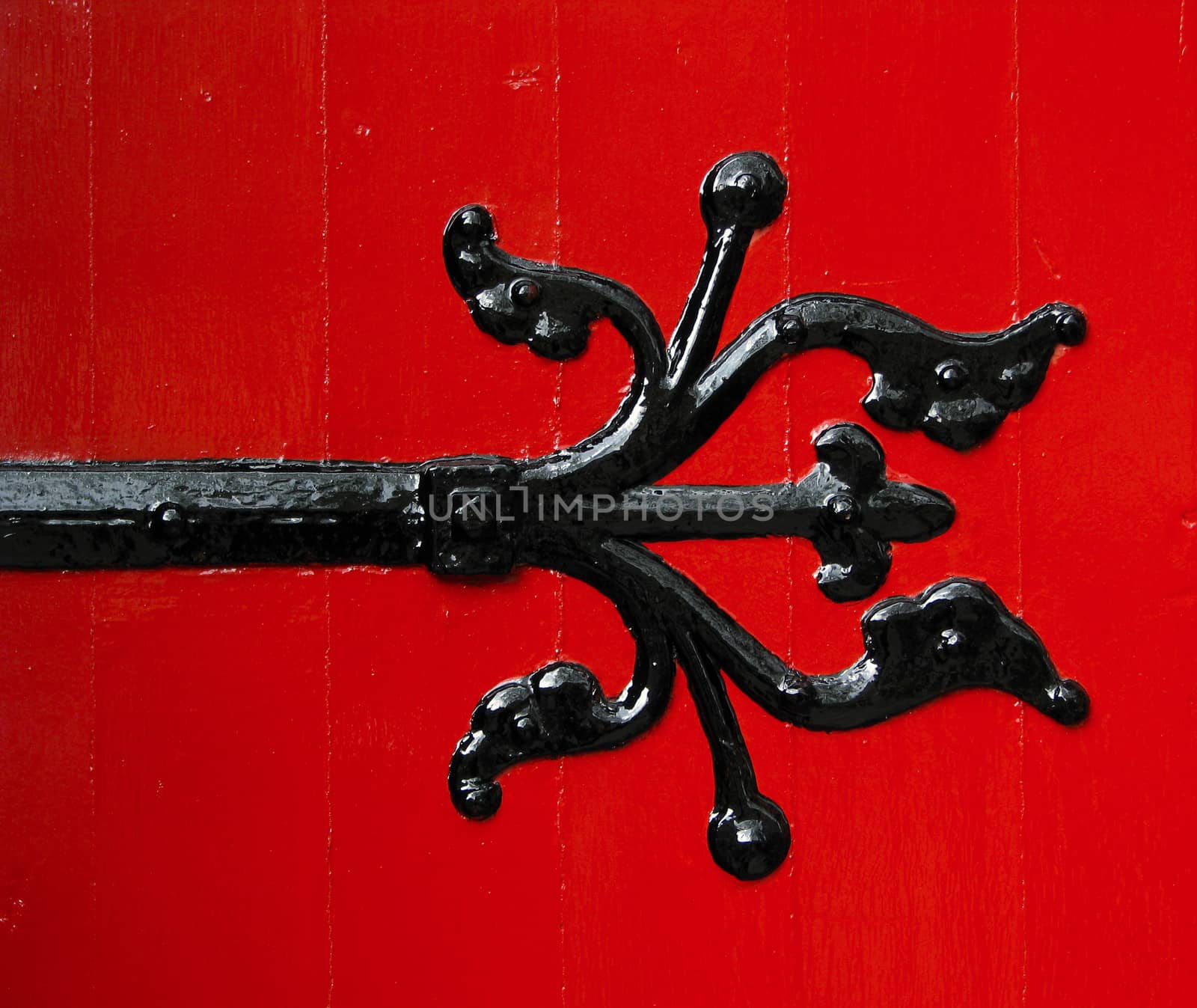 A Black Ornamental Hinge On Freshly Painted Red Door