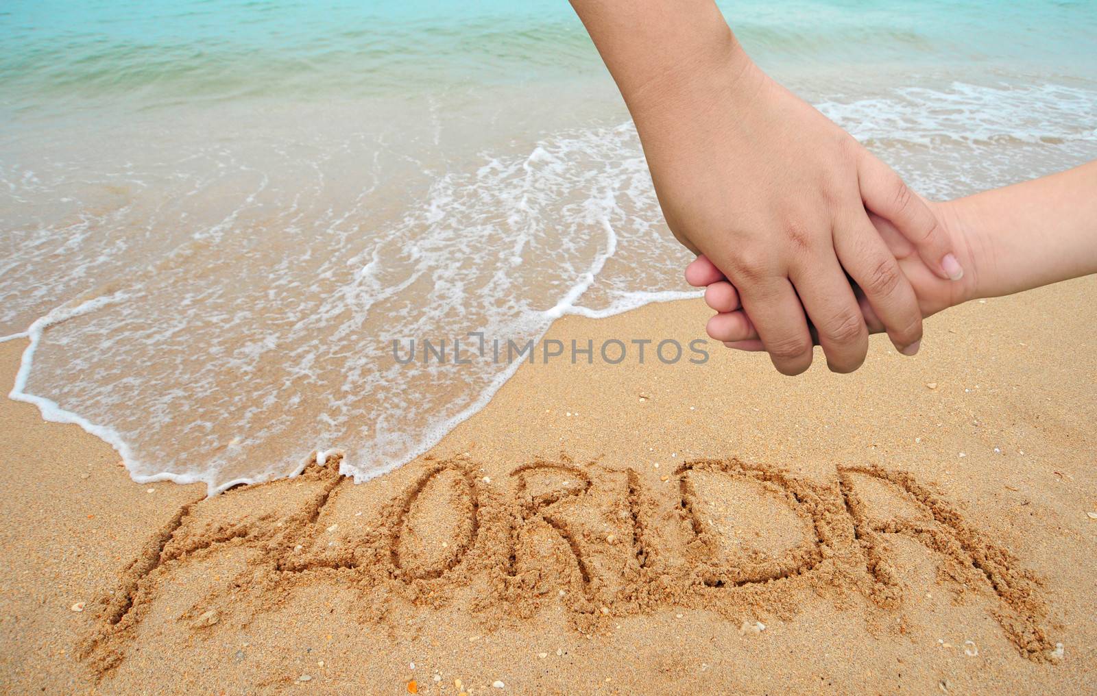 A mother holding the hand of a child in Florida next to the ocean